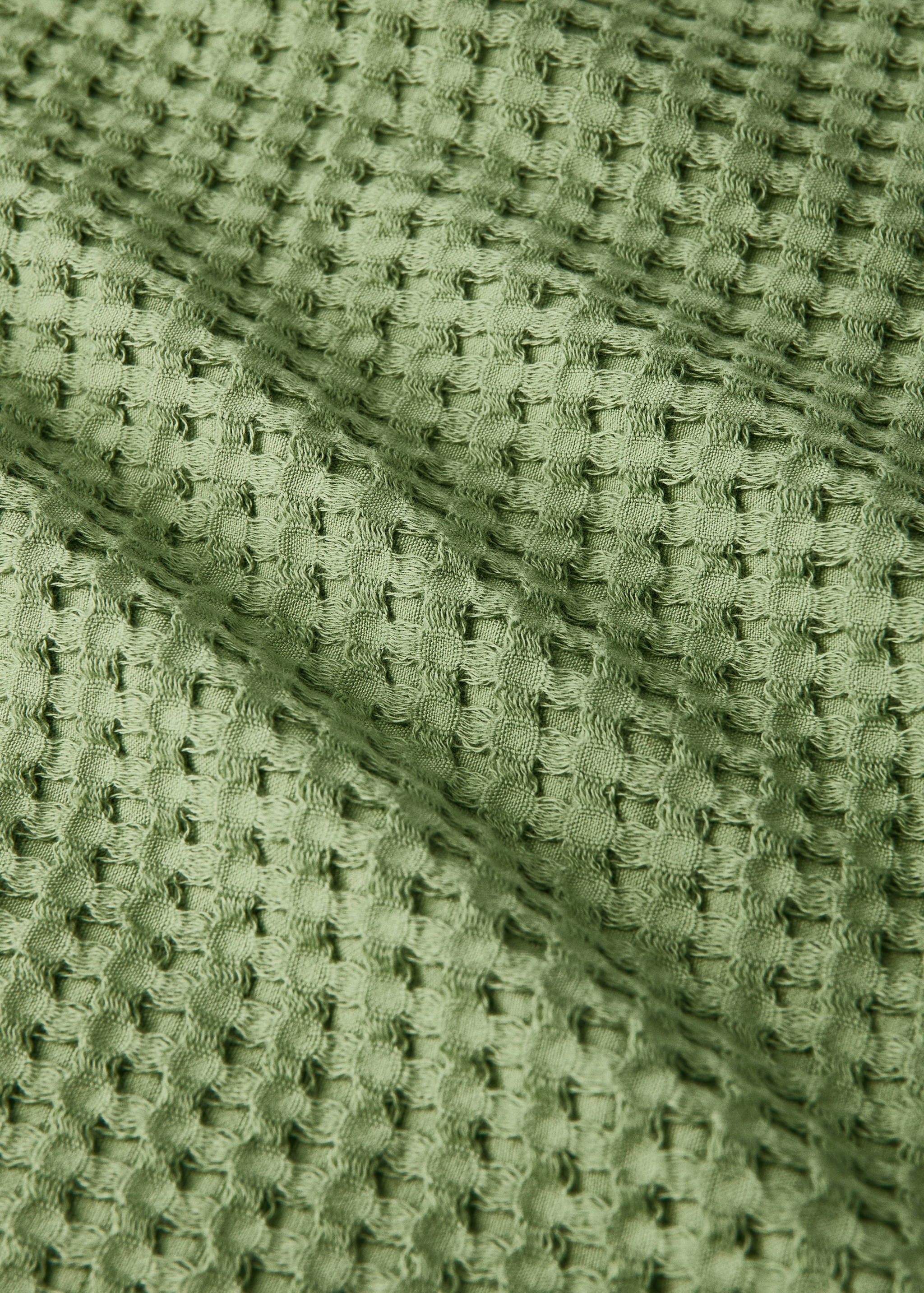 Close-up of a sage green waffle-weave towel texture.