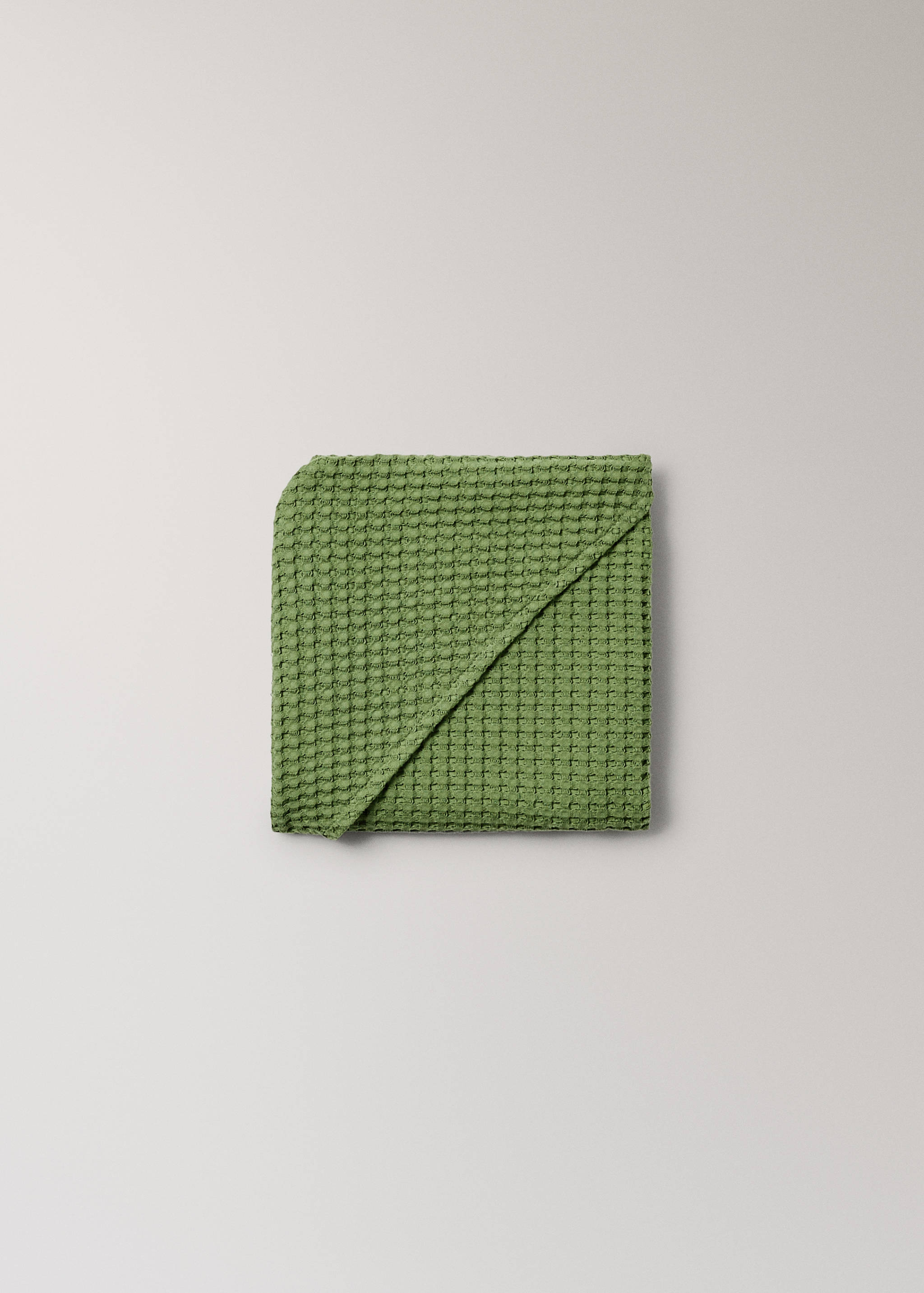 Green waffle-weave towel in a close-up product view.