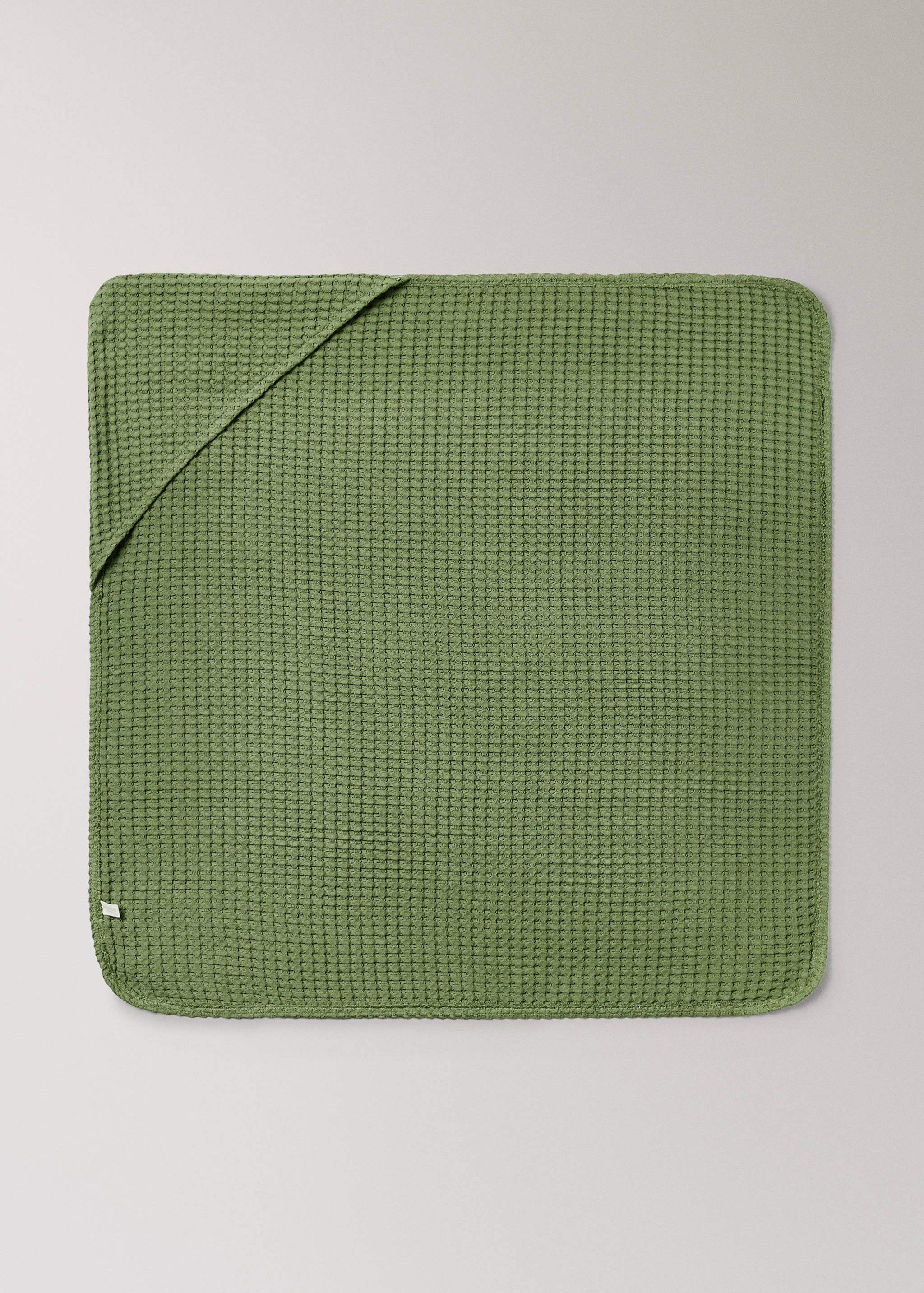 Green waffle-weave towel with a hooded corner.