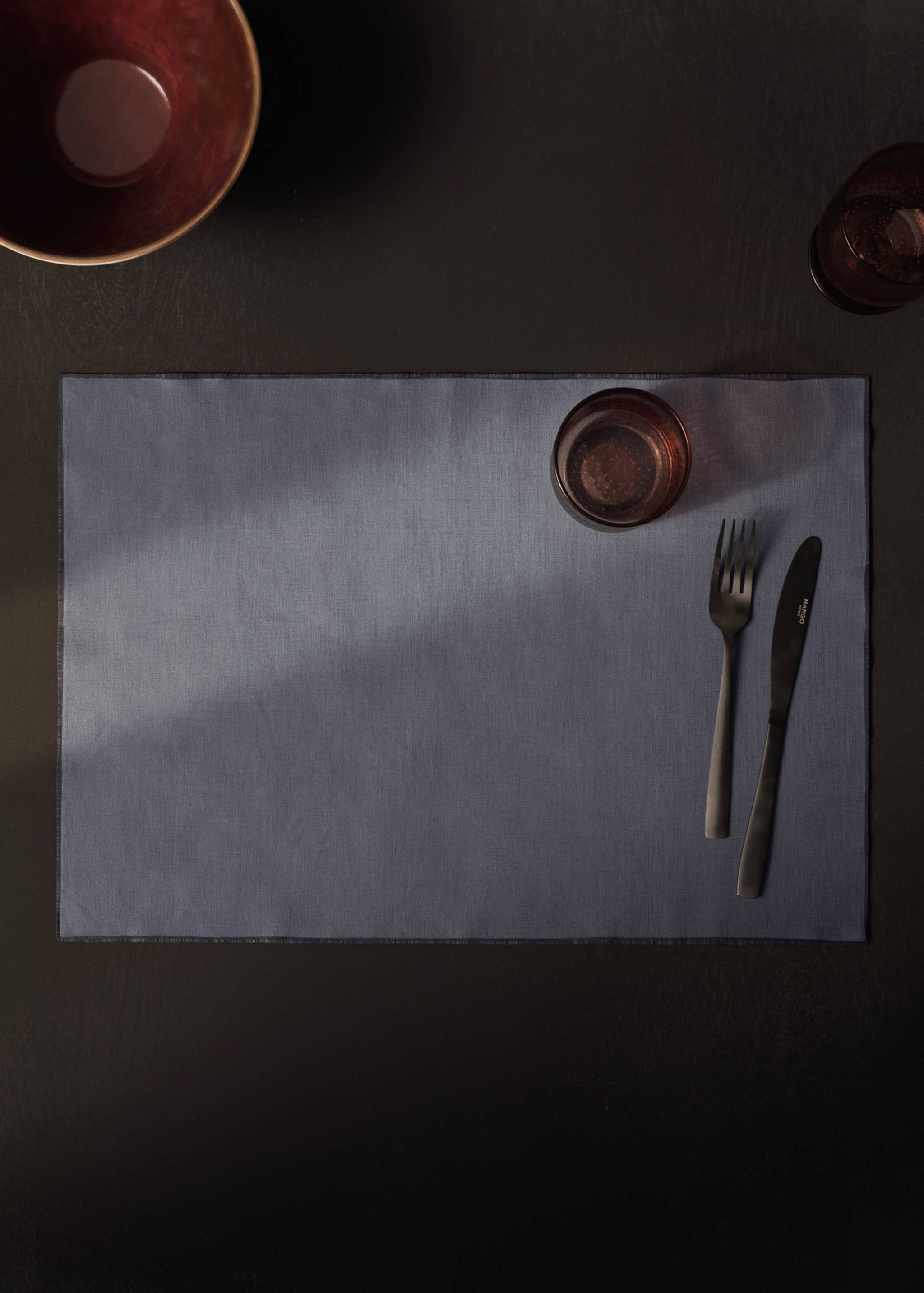 Dark blue placemat on a table with cutlery and glassware.