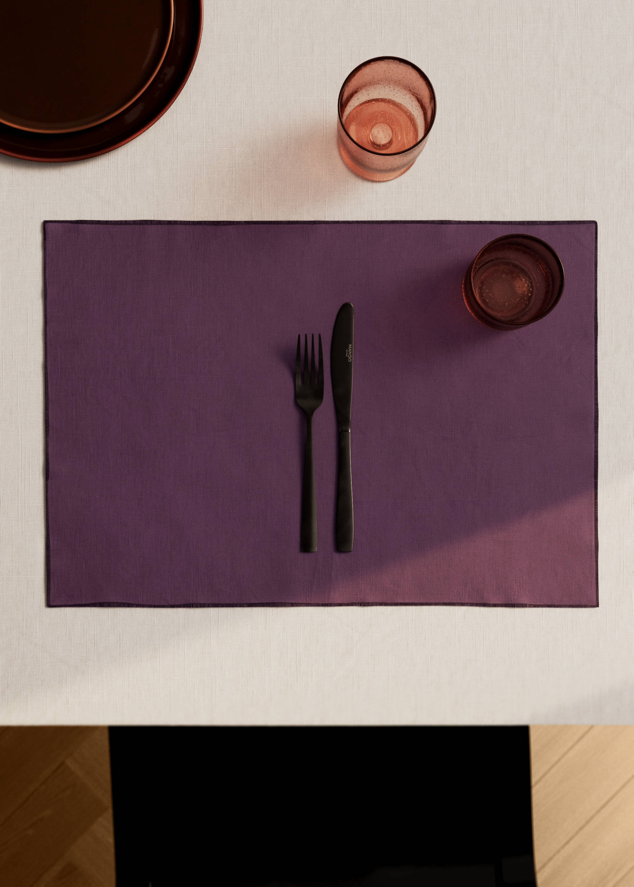Rectangular purple place mat styled with cutlery and glassware.