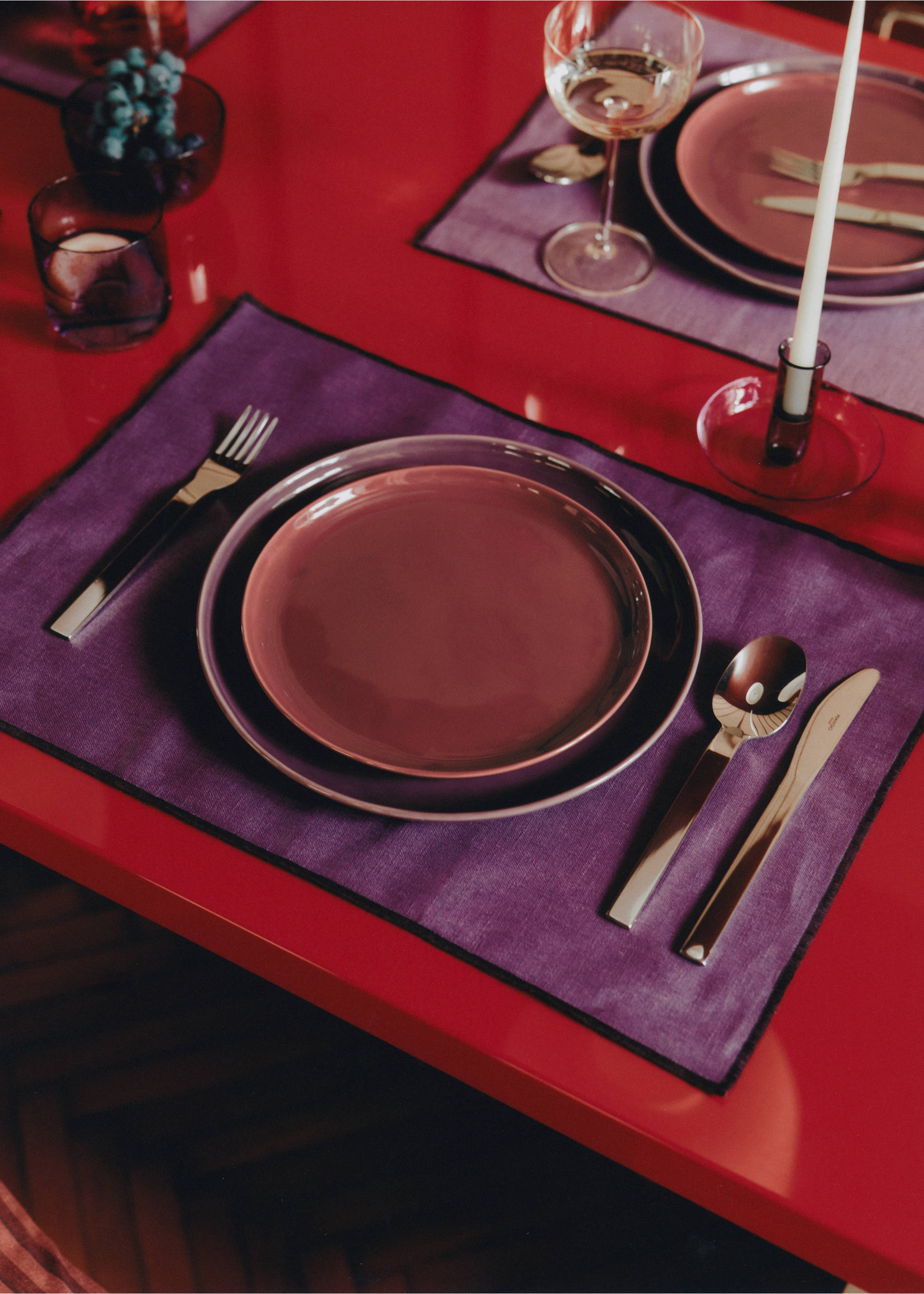 Purple placemat with black border on a red dining table., Blackberry. Ref: 17024133-00.