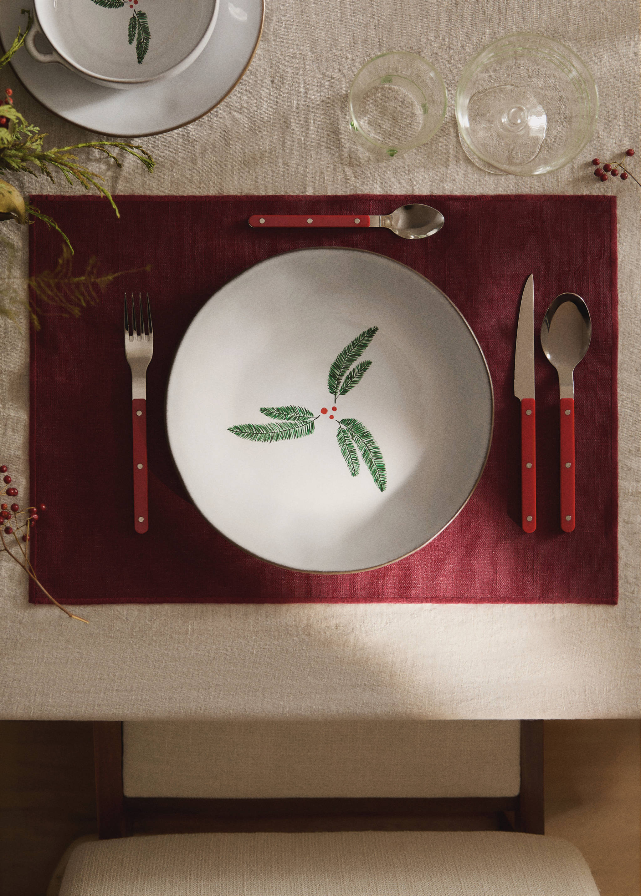 Burgundy placemat styled on a table setting with festive tableware.
