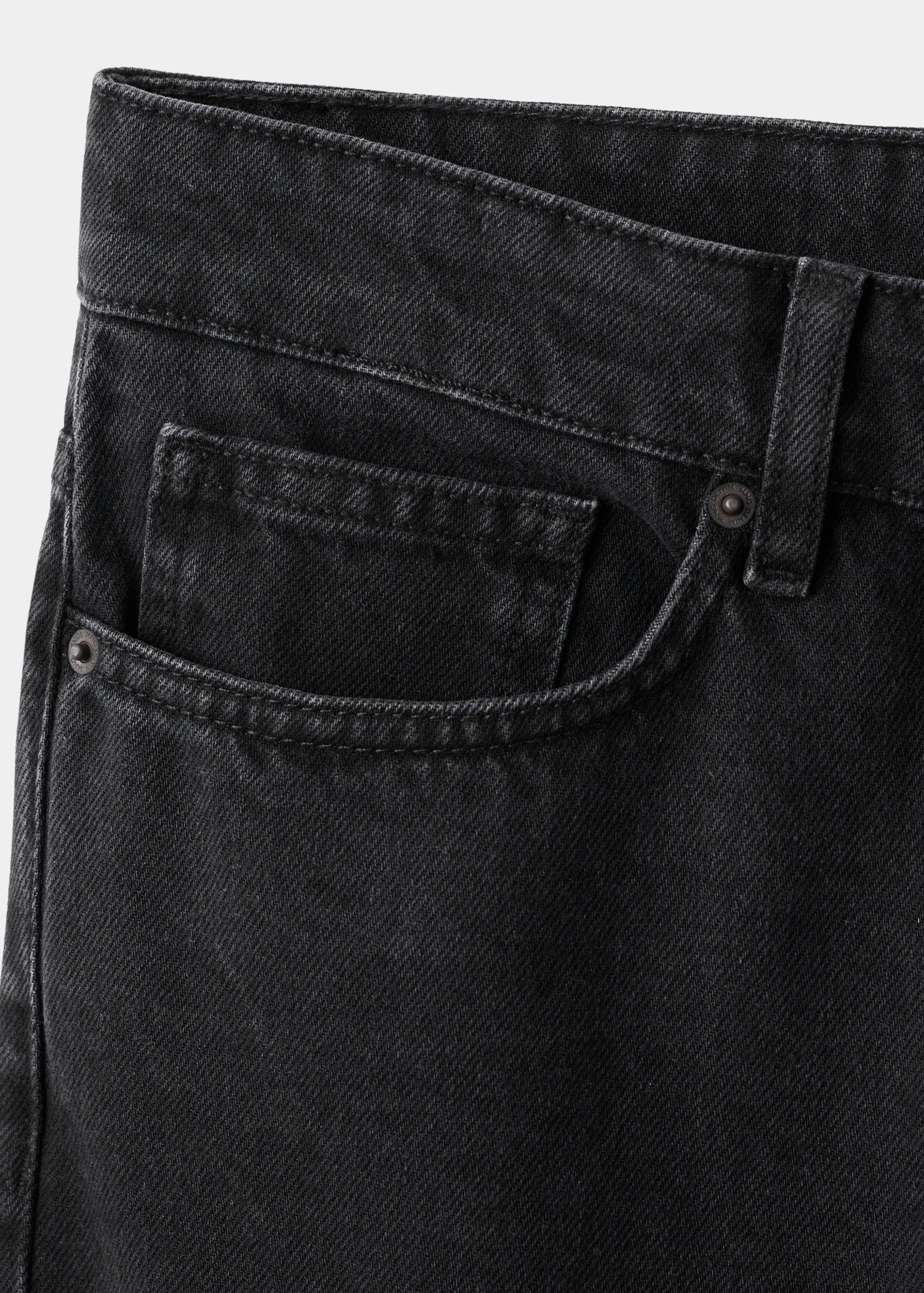 Close-up of black denim trousers showing the front pocket detail.