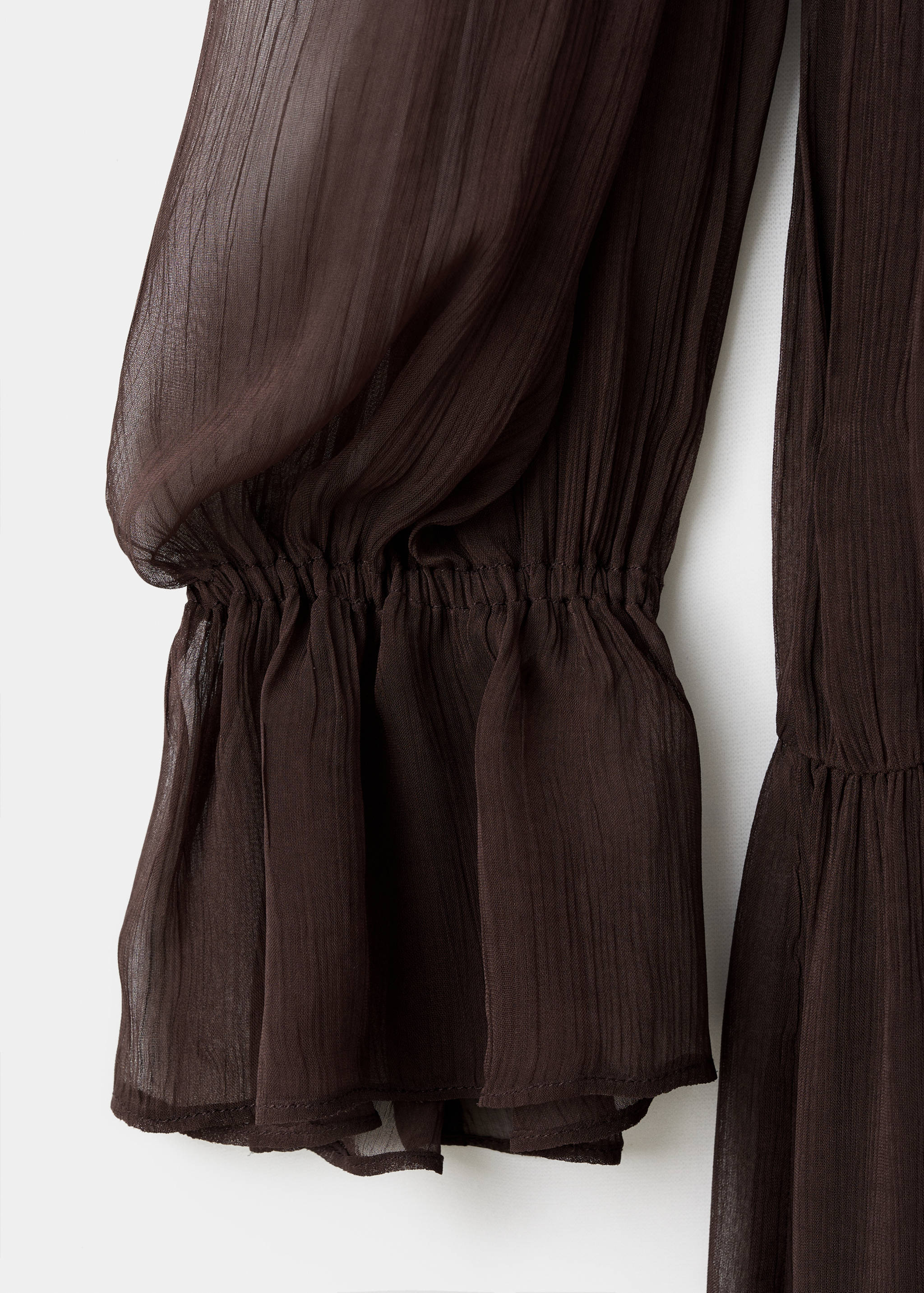 Close-up of a dark brown dress sleeve with elastic smocking and a ruffled cuff.