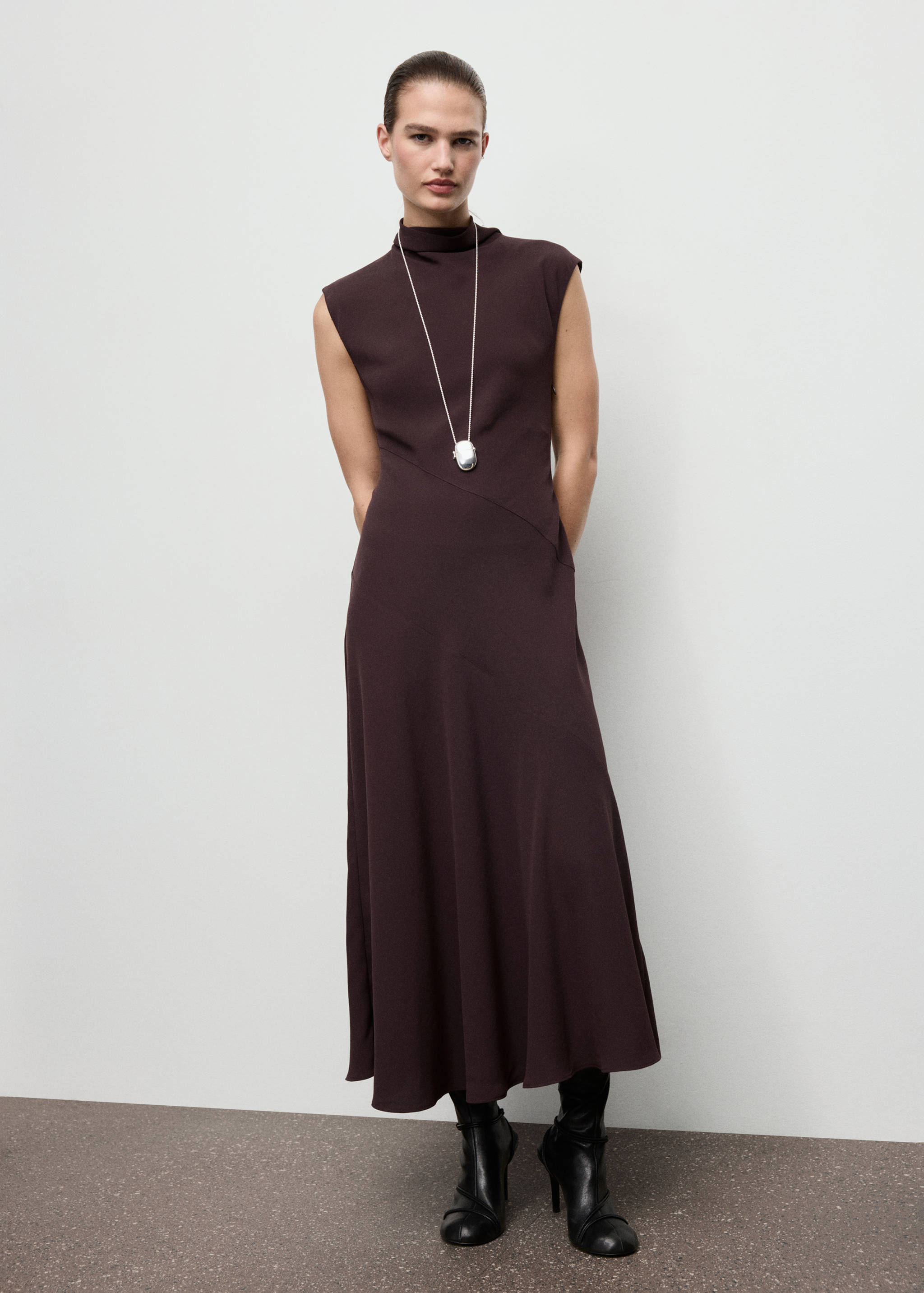 Dark plum midi dress with a high mock neck, sleeveless cut, and diagonal waist seam.