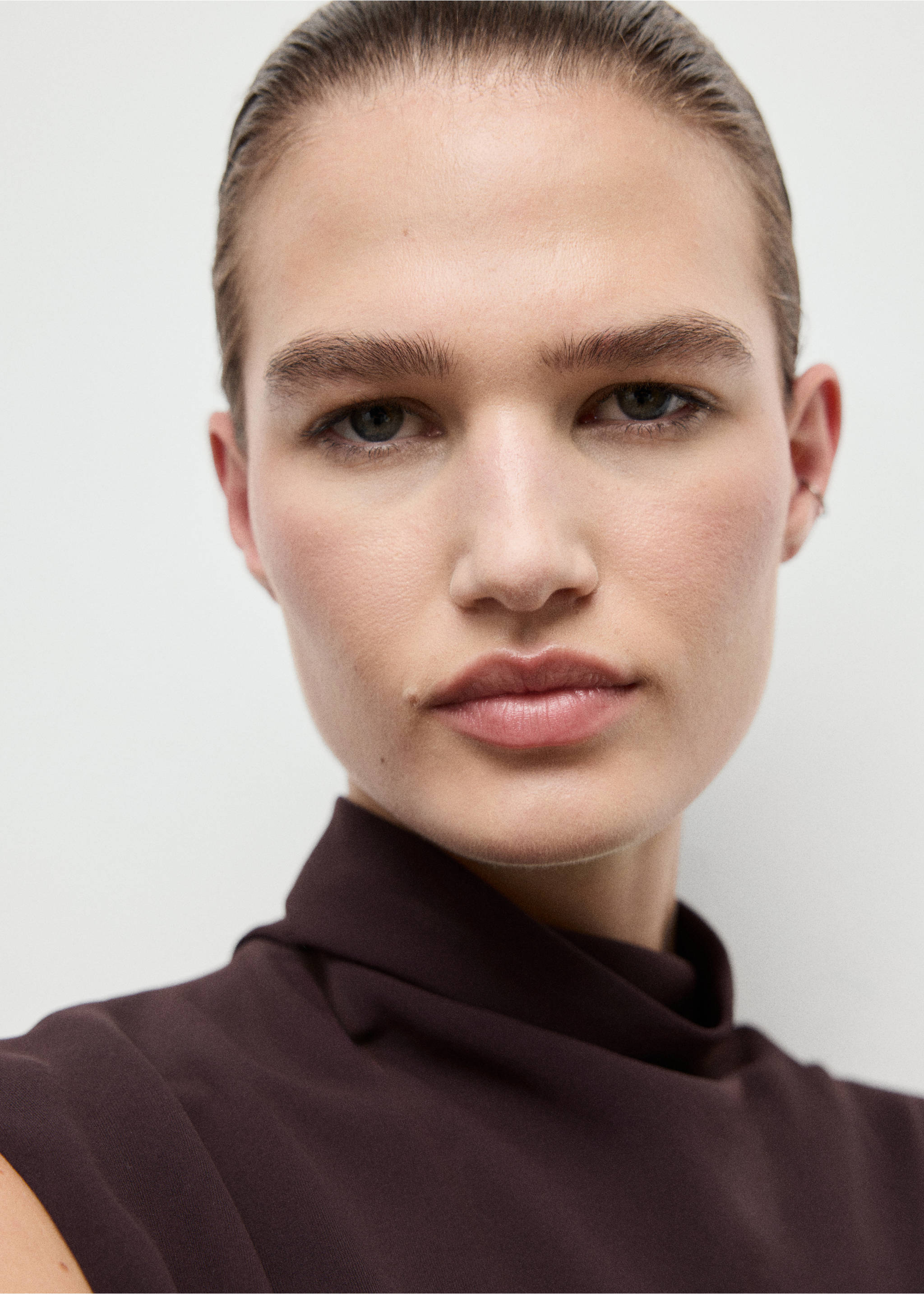 Close-up of a model wearing a dark brown sleeveless dress with a draped high neckline., Brown. Ref: 17025818-00.