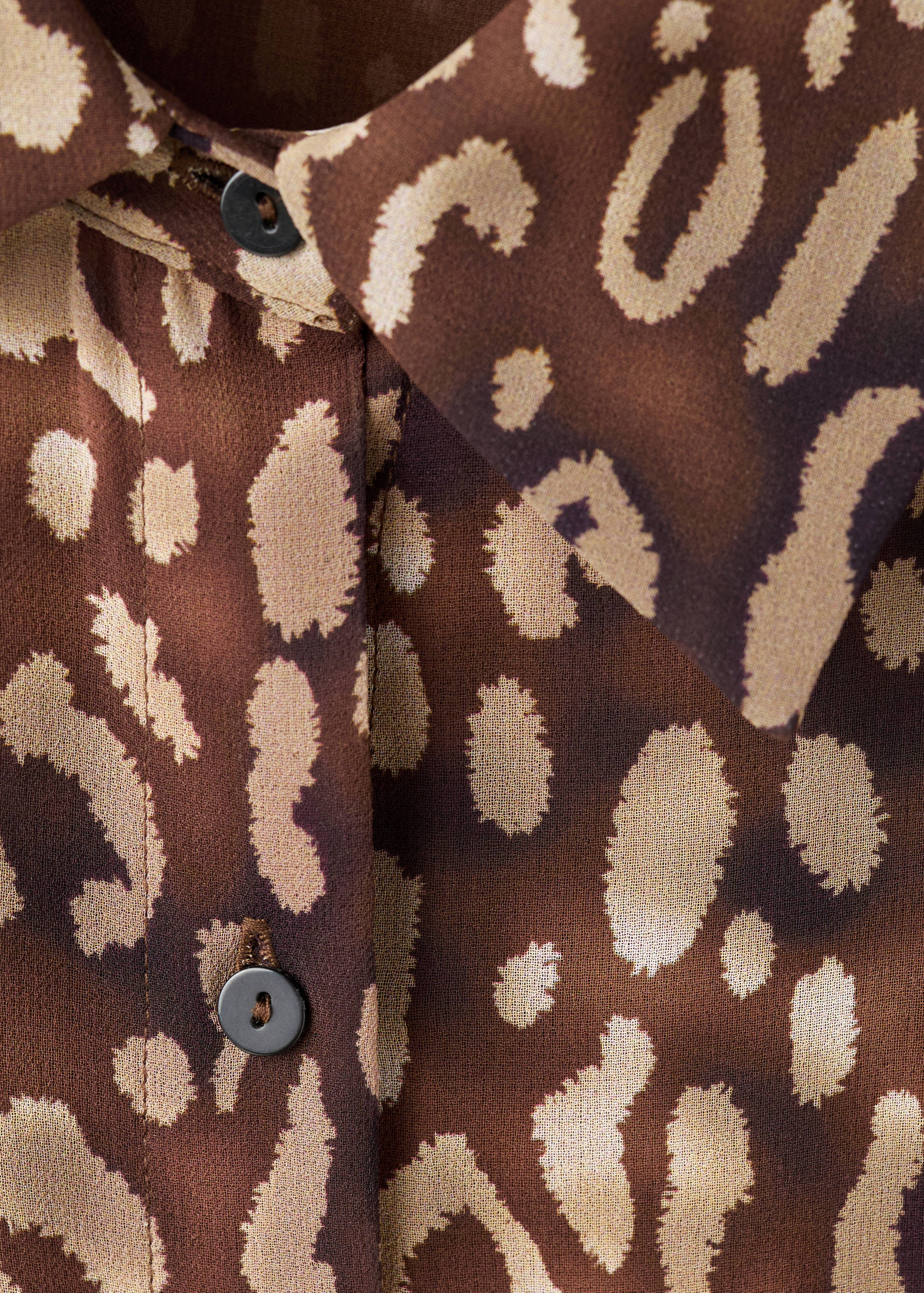 Close-up of a brown animal print dress collar and button detail.