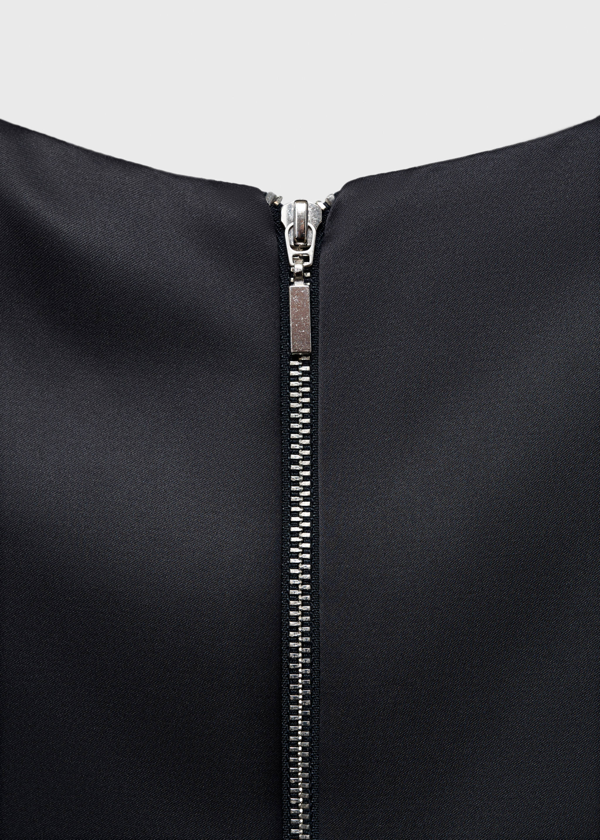 Close-up of the back zip closure on a black dress.