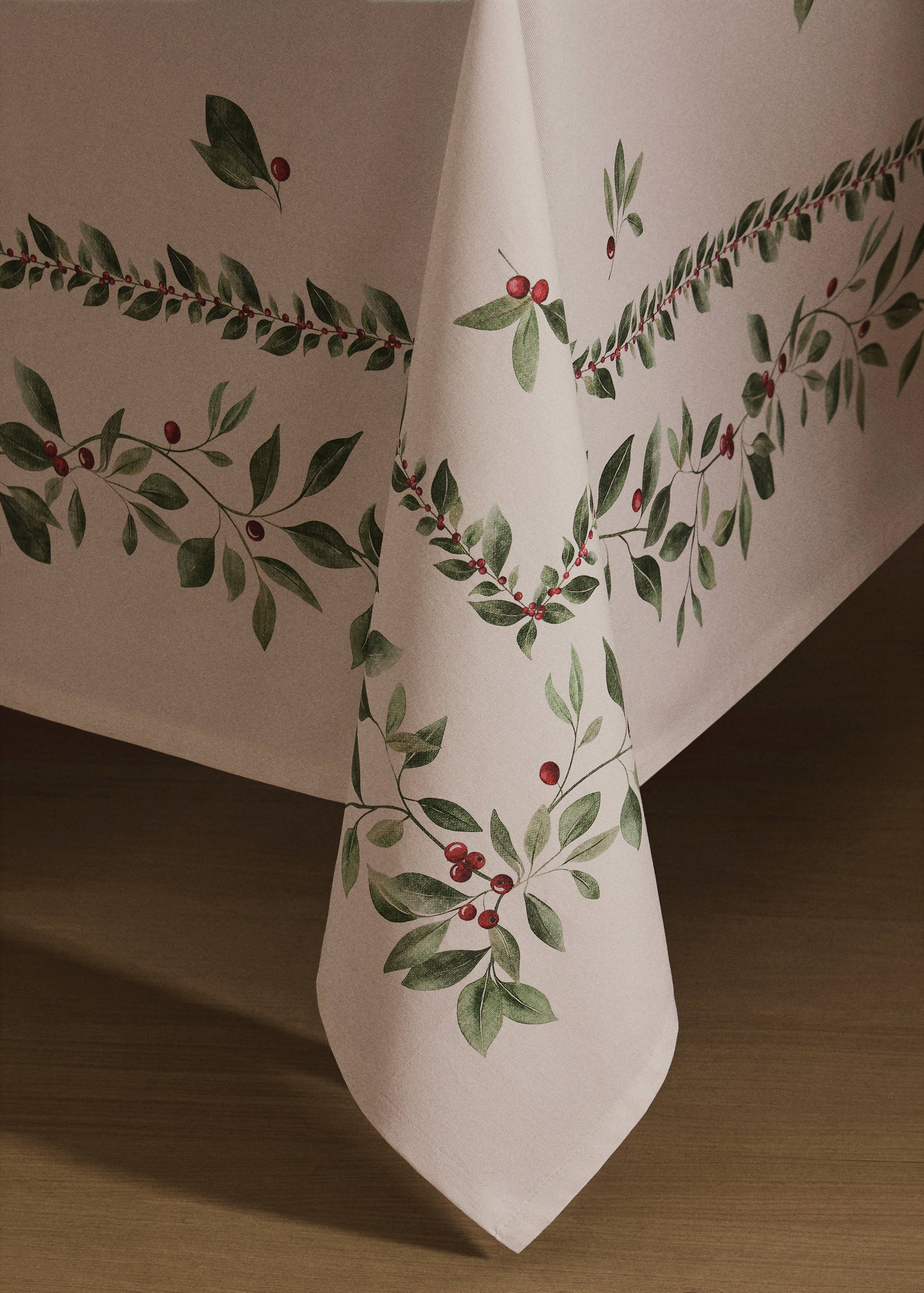 Cream tablecloth with a green leaf and red berry botanical print.