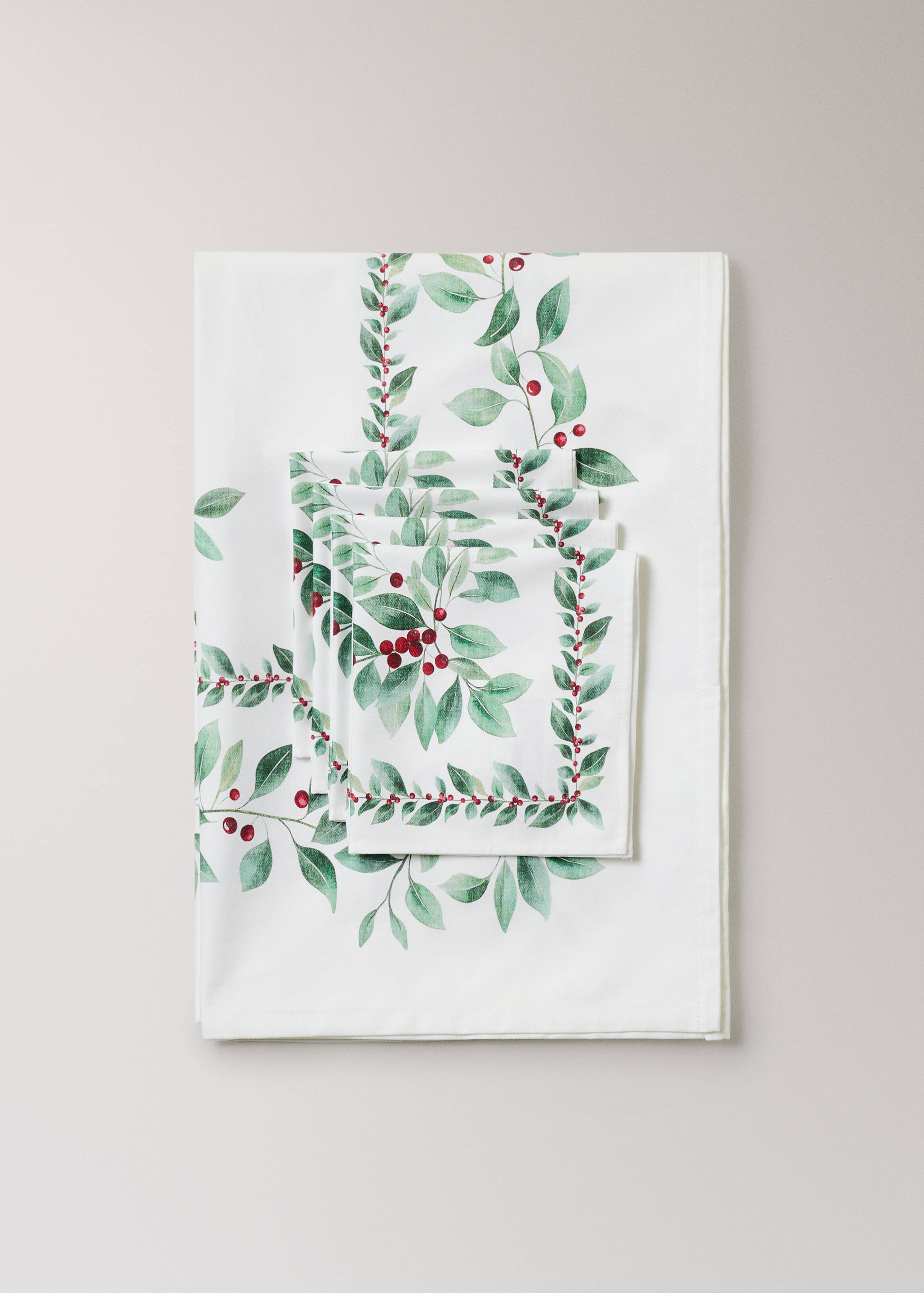 White tablecloth and napkins with a botanical leaf and red berry print.