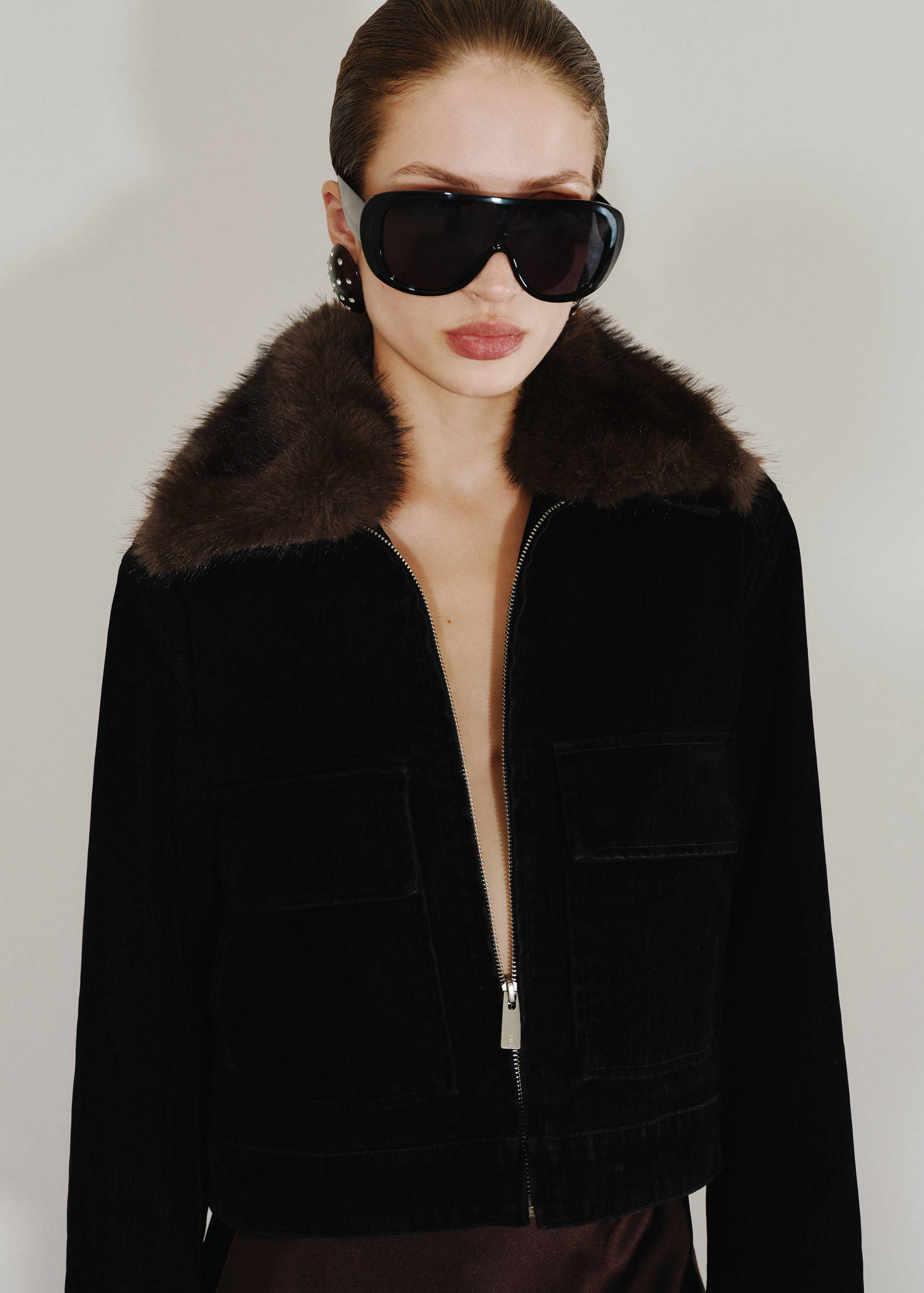 Black zip-up jacket with a brown faux-fur collar and chest pockets.