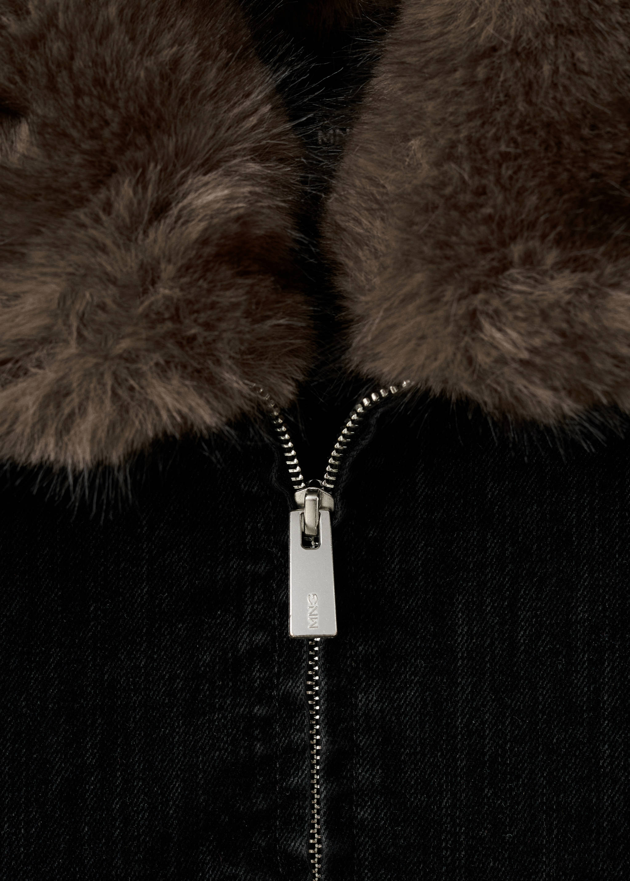 Jacket fabric detail showing a brown faux-fur collar and silver zip.