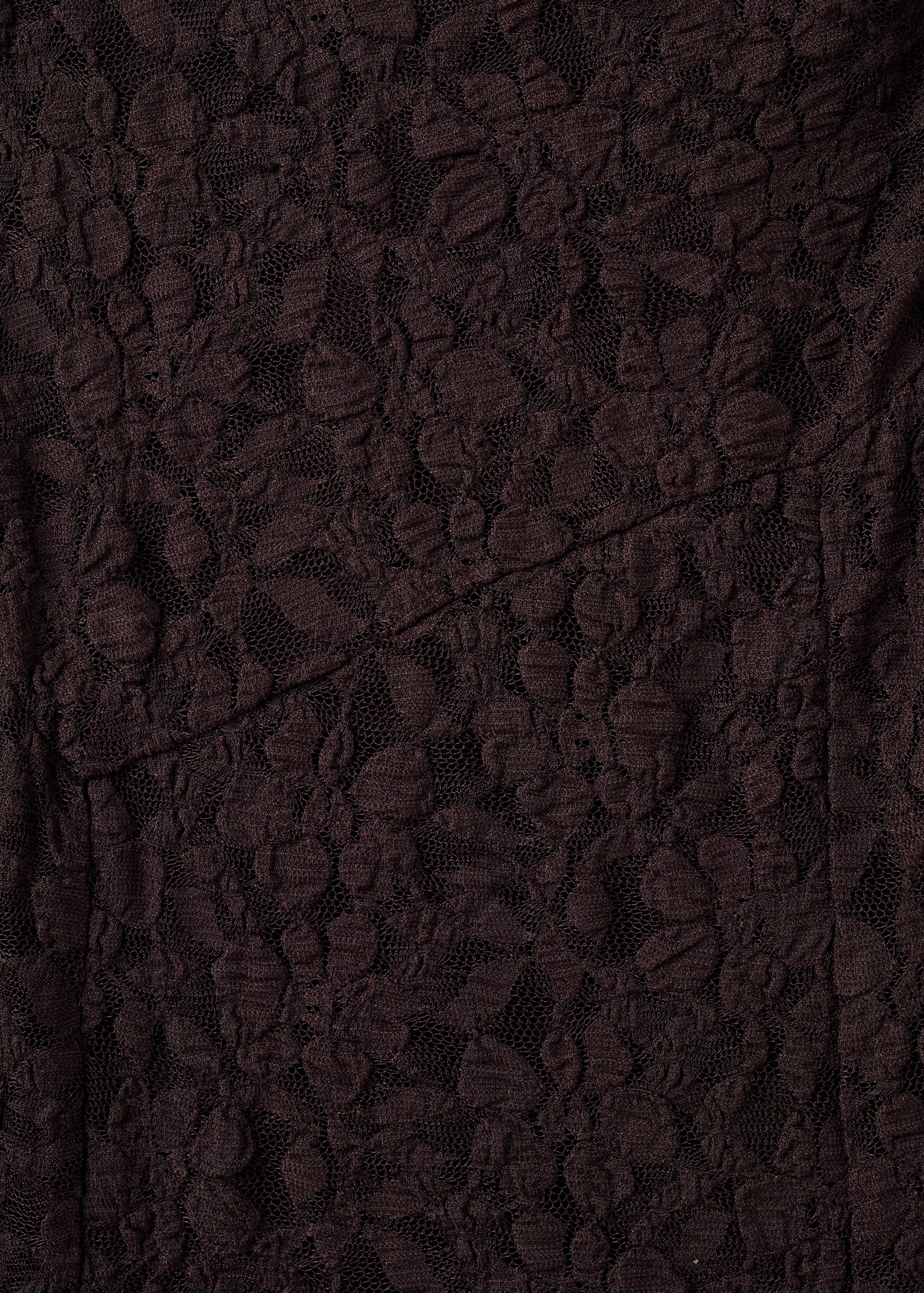 Close-up of the dark burgundy floral lace fabric on a dress.