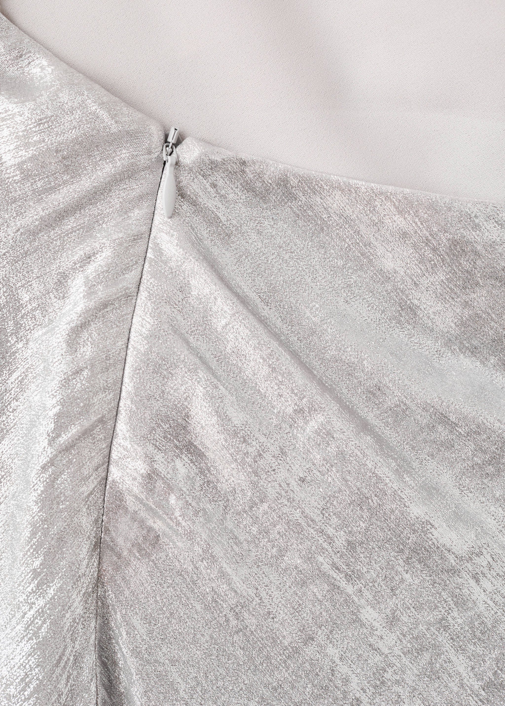 Close-up of the metallic silver fabric and concealed zip detail on the dress.
