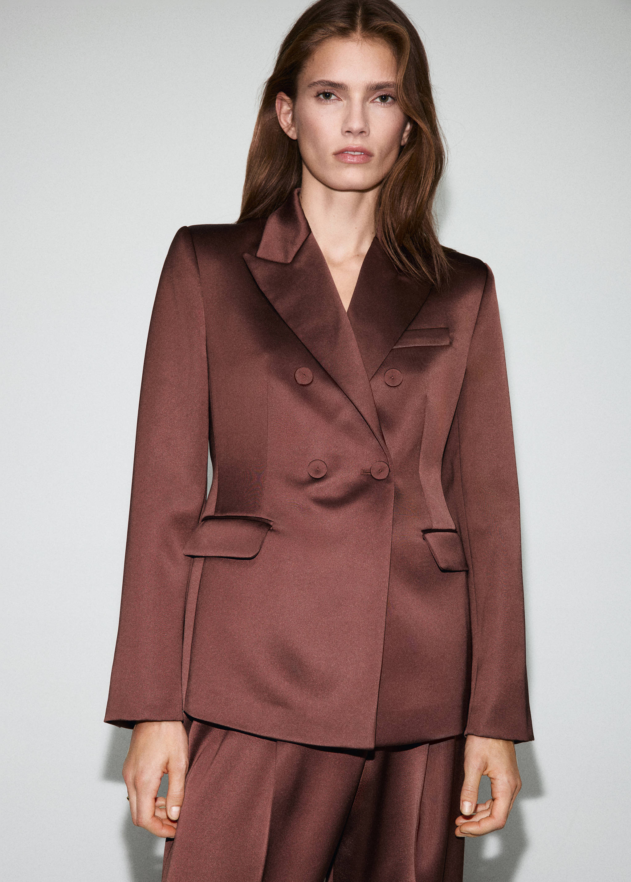 Brown double-breasted satin blazer with peaked lapels and front pockets.