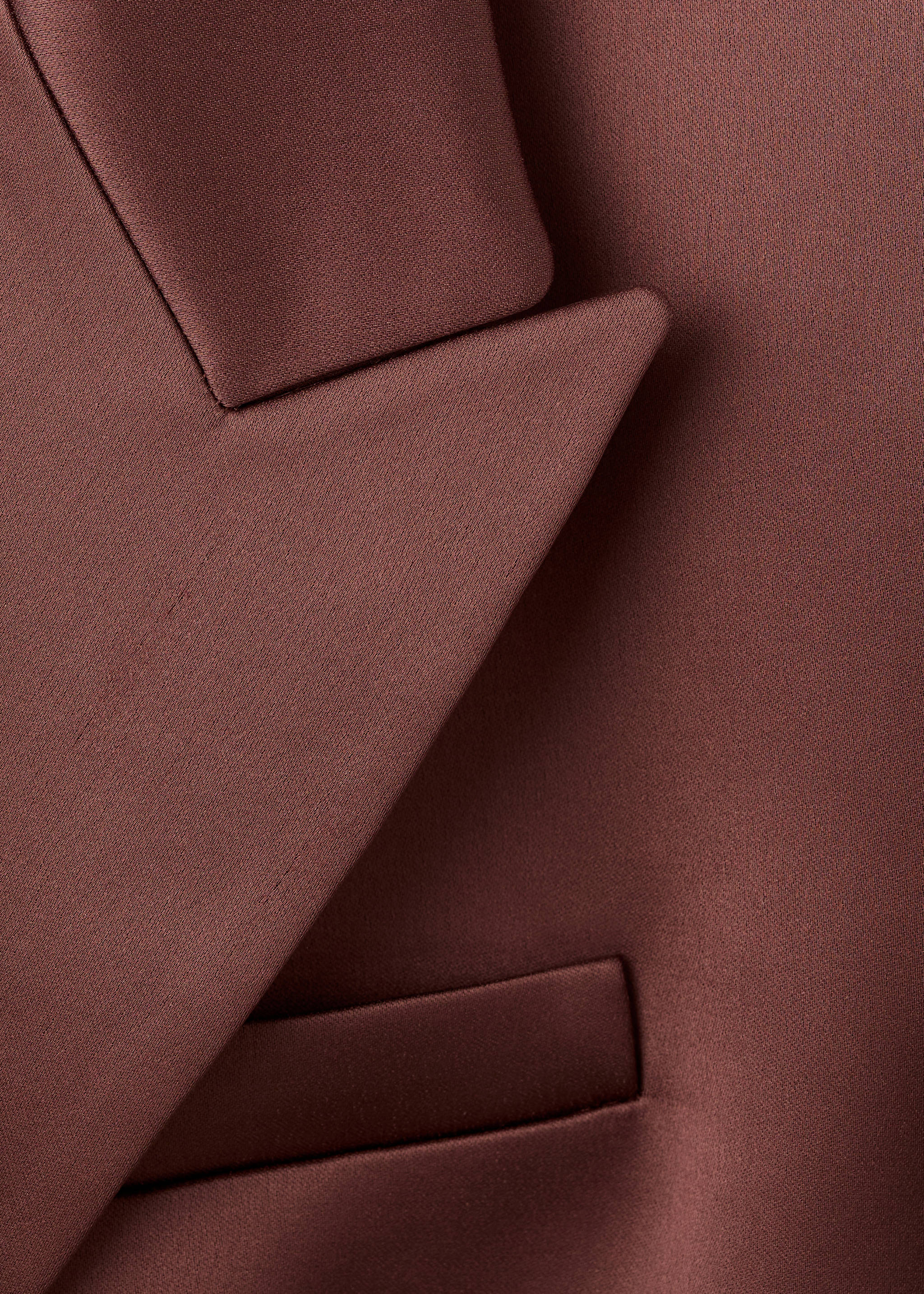 Close-up of a brown blazer showing the lapel and pocket.