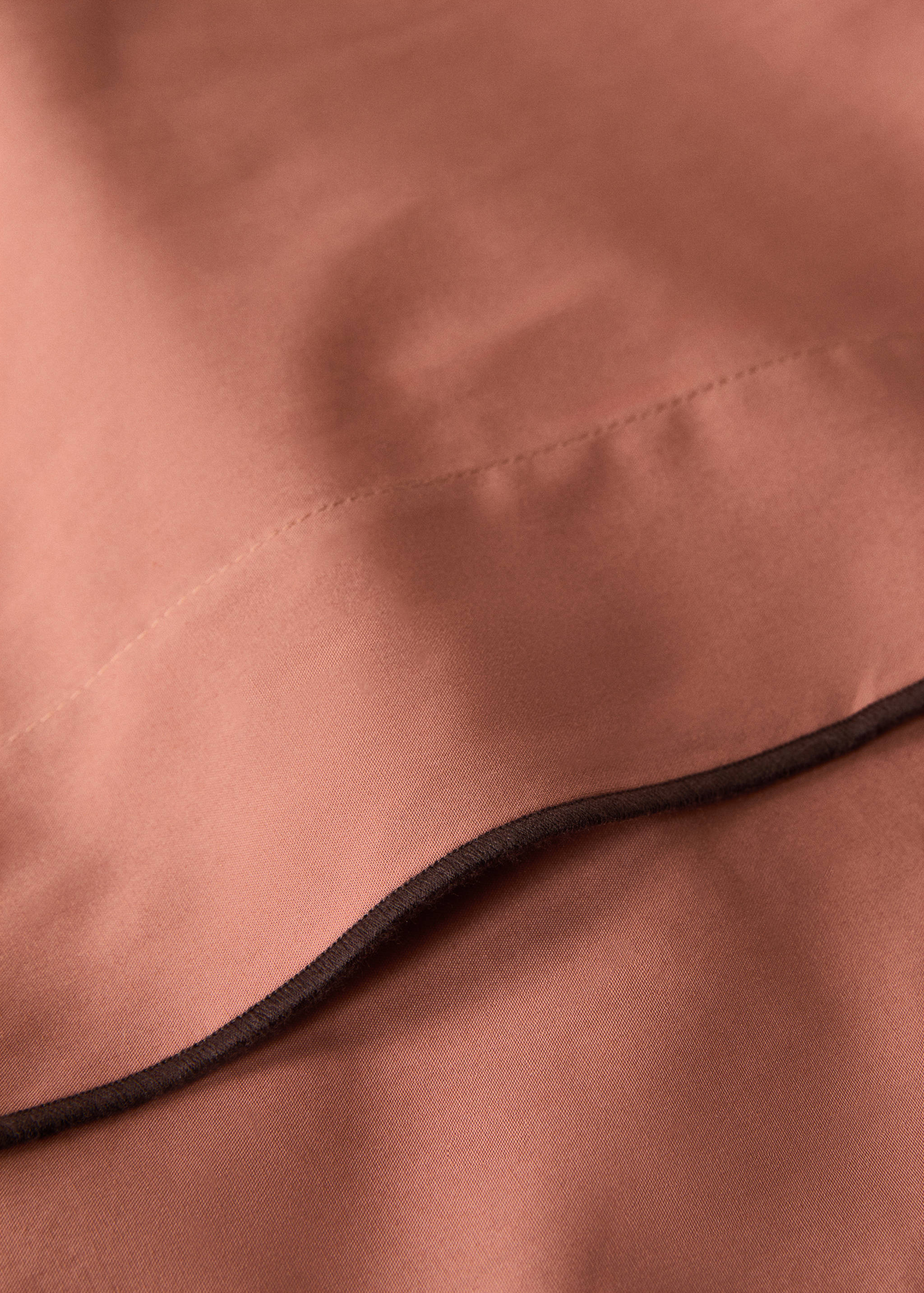 Terracotta flat sheet detail with contrasting dark brown piping.