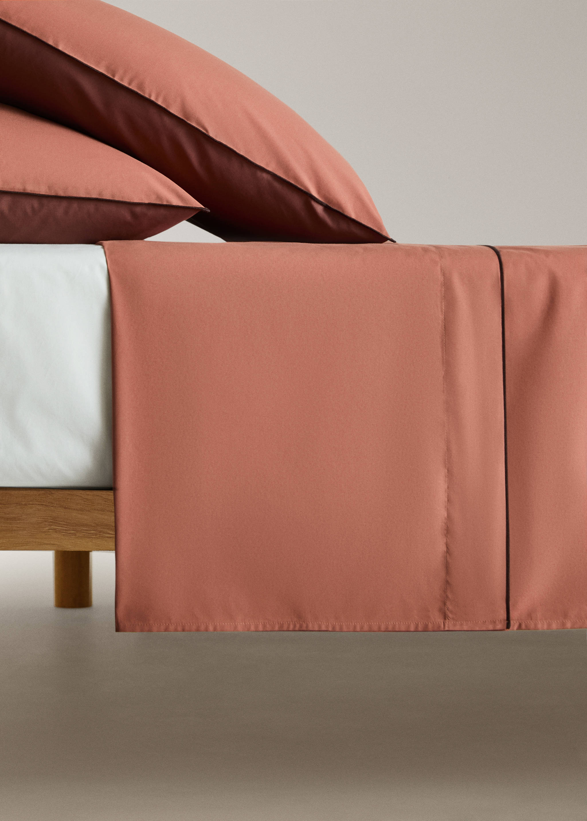 Terracotta flat sheet with dark piping trim.