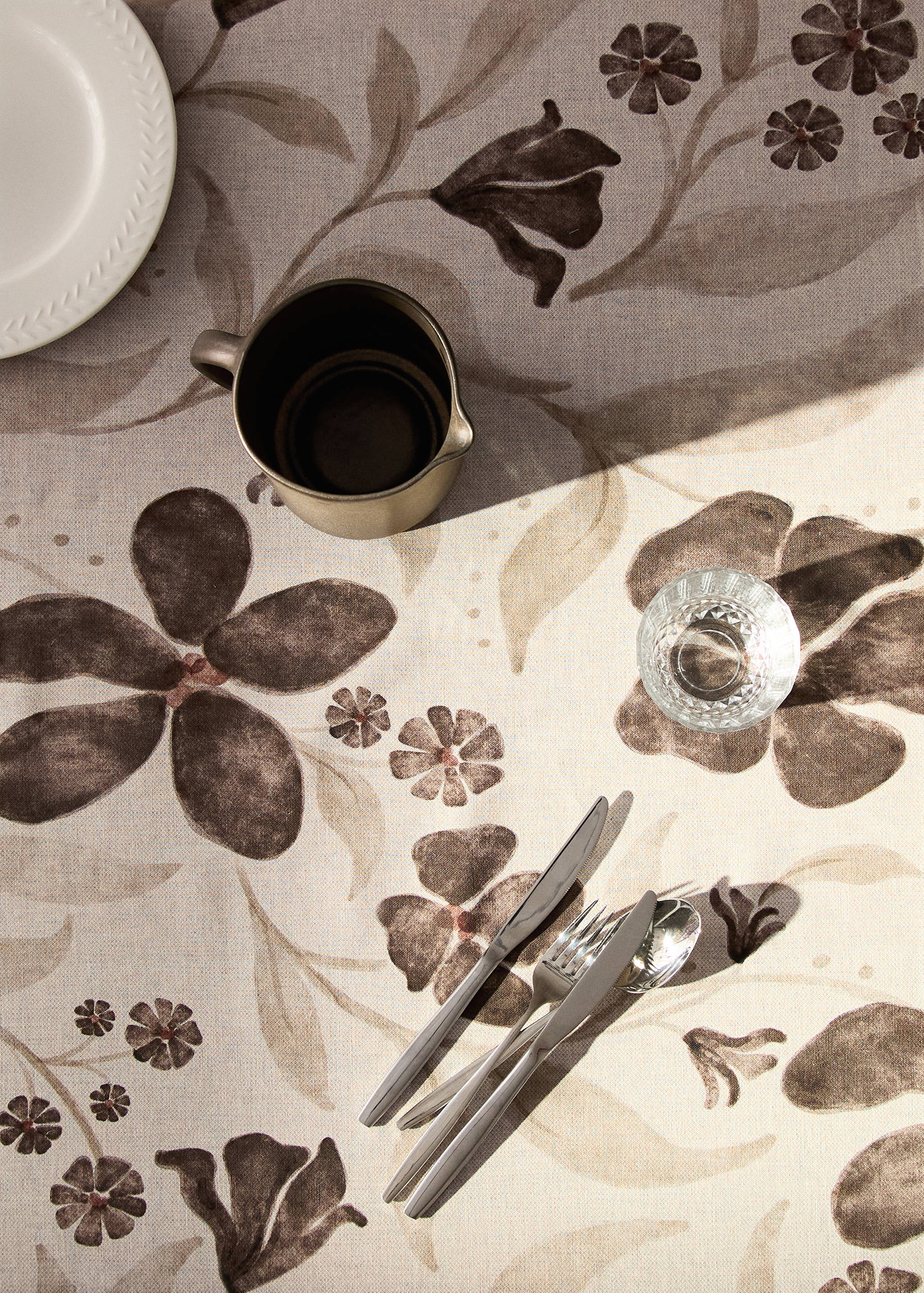 Brown and beige floral print tablecloth styled with tableware.