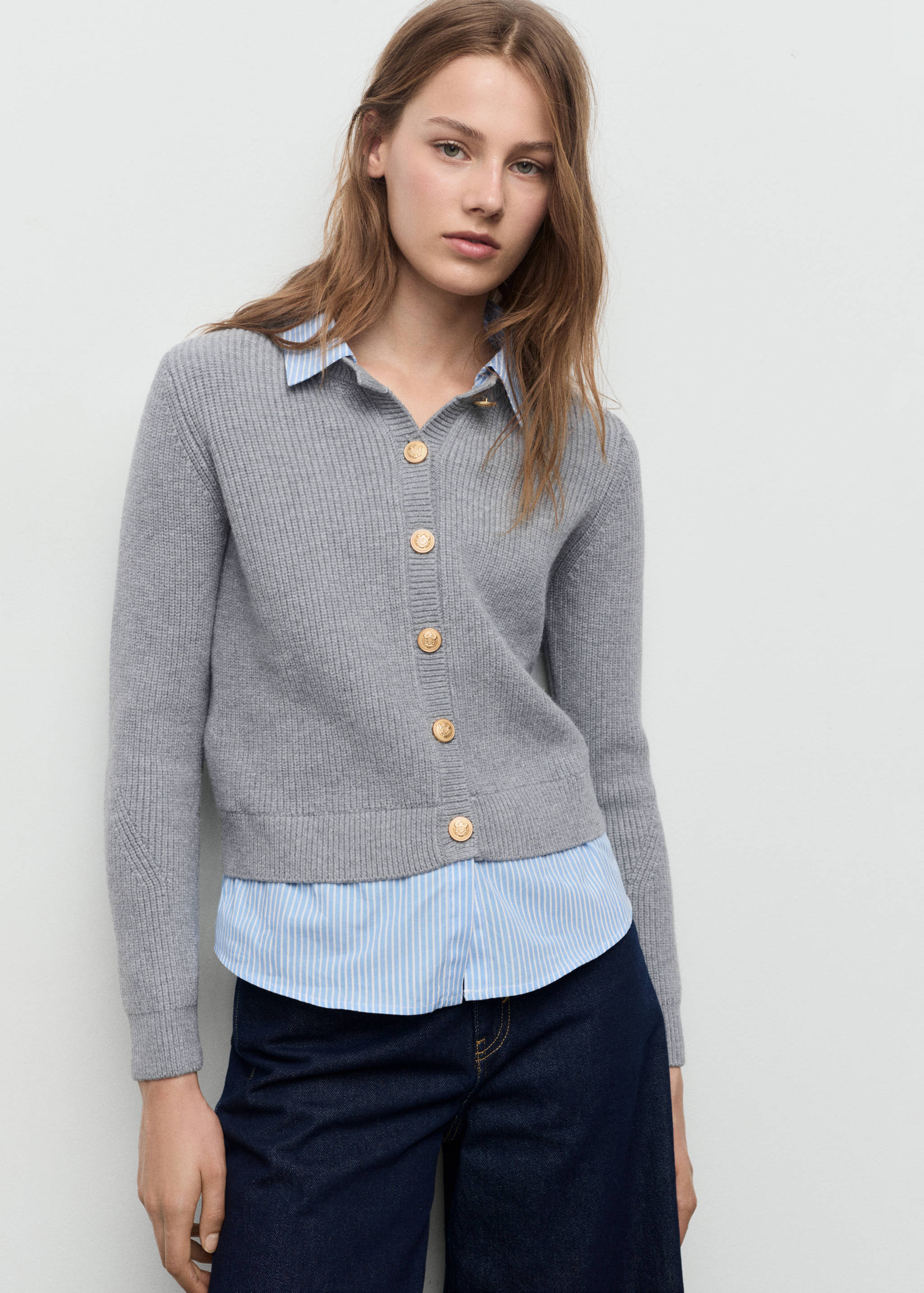 Grey ribbed knit cardigan with gold-toned buttons, layered over a striped shirt.