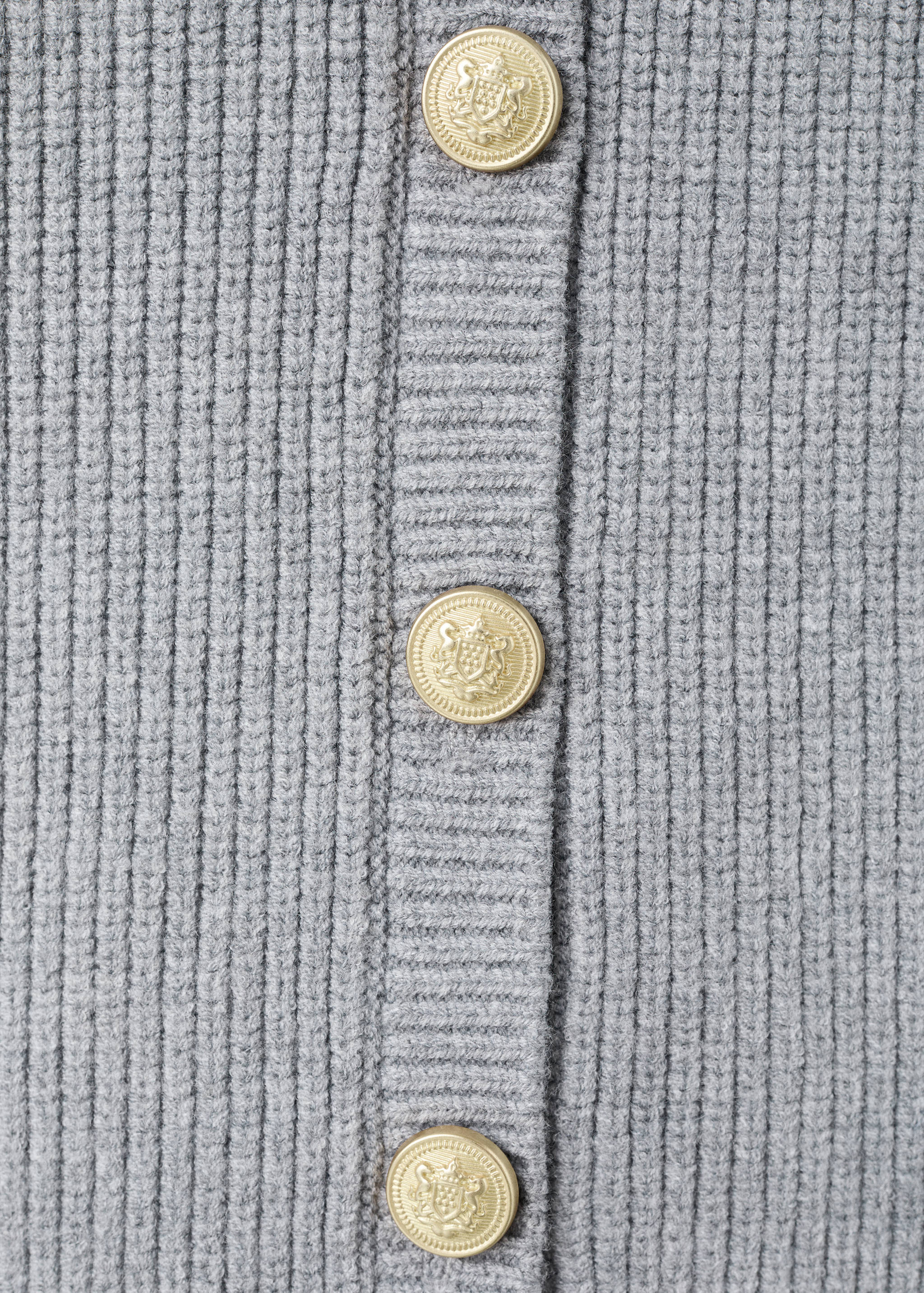 Close-up of a grey ribbed cardigan with gold embossed buttons.