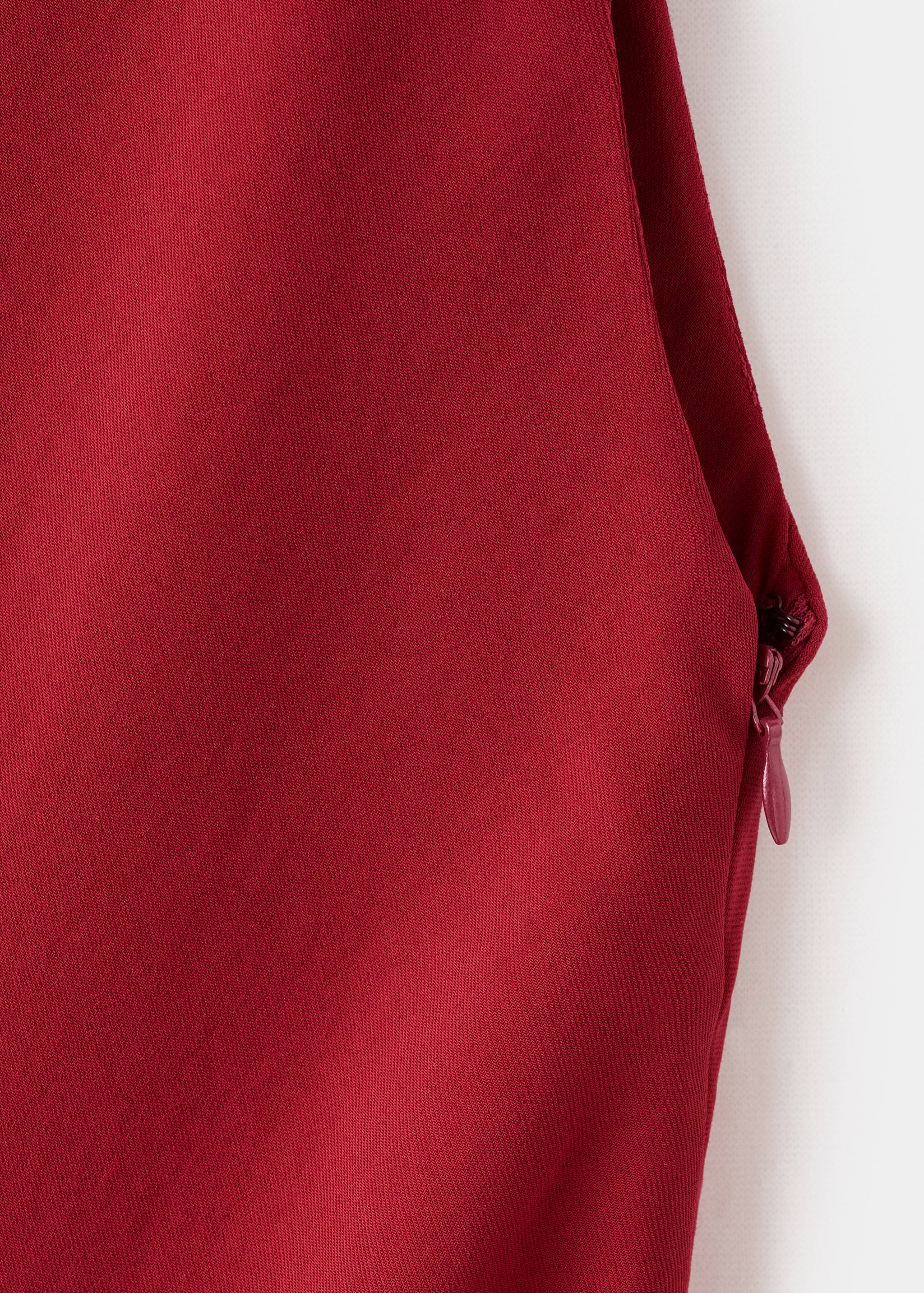Close-up of the dark red fabric and side zip of the dress.