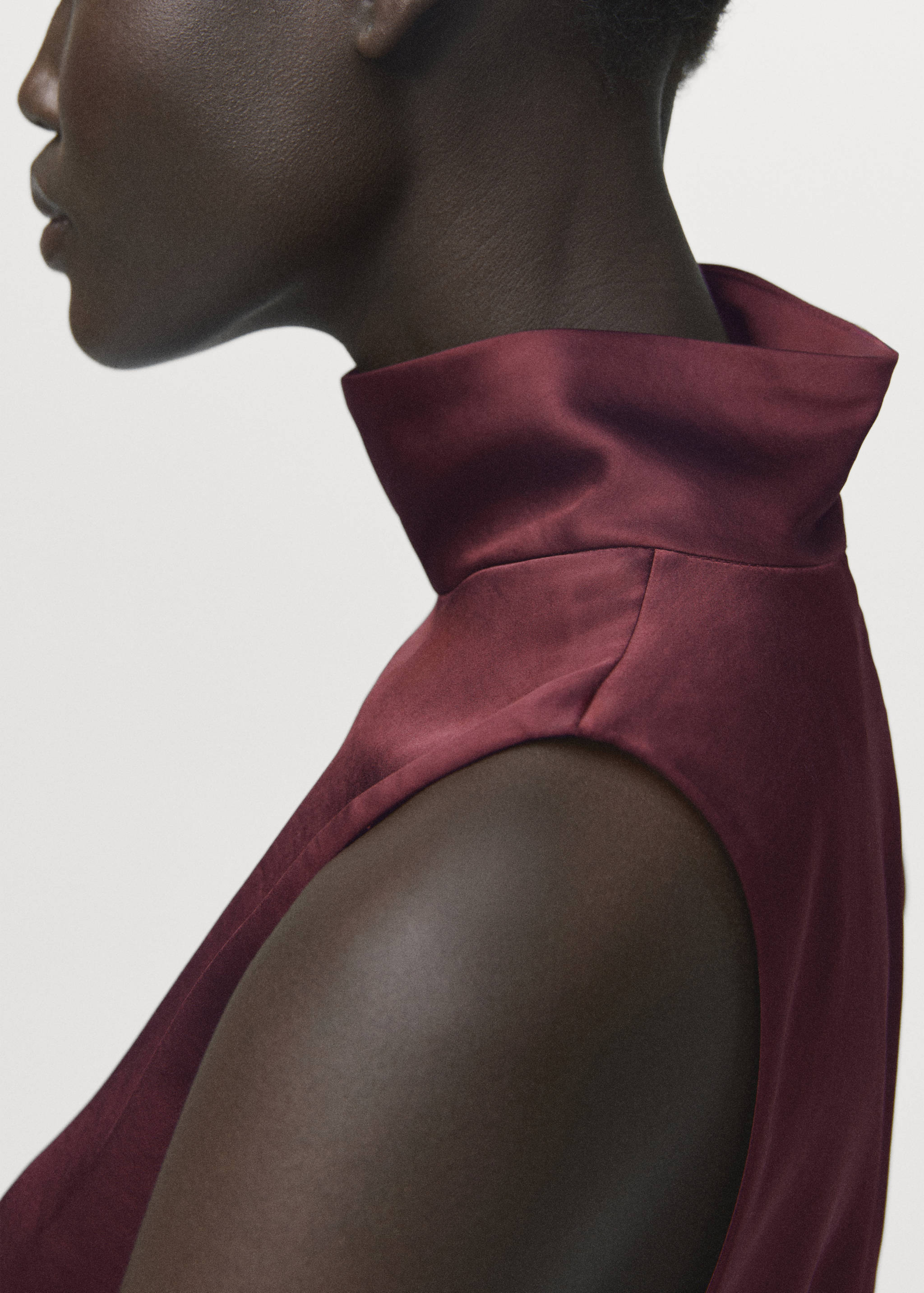Burgundy satin sleeveless blouse with a high mock neck, seen in a close-up.