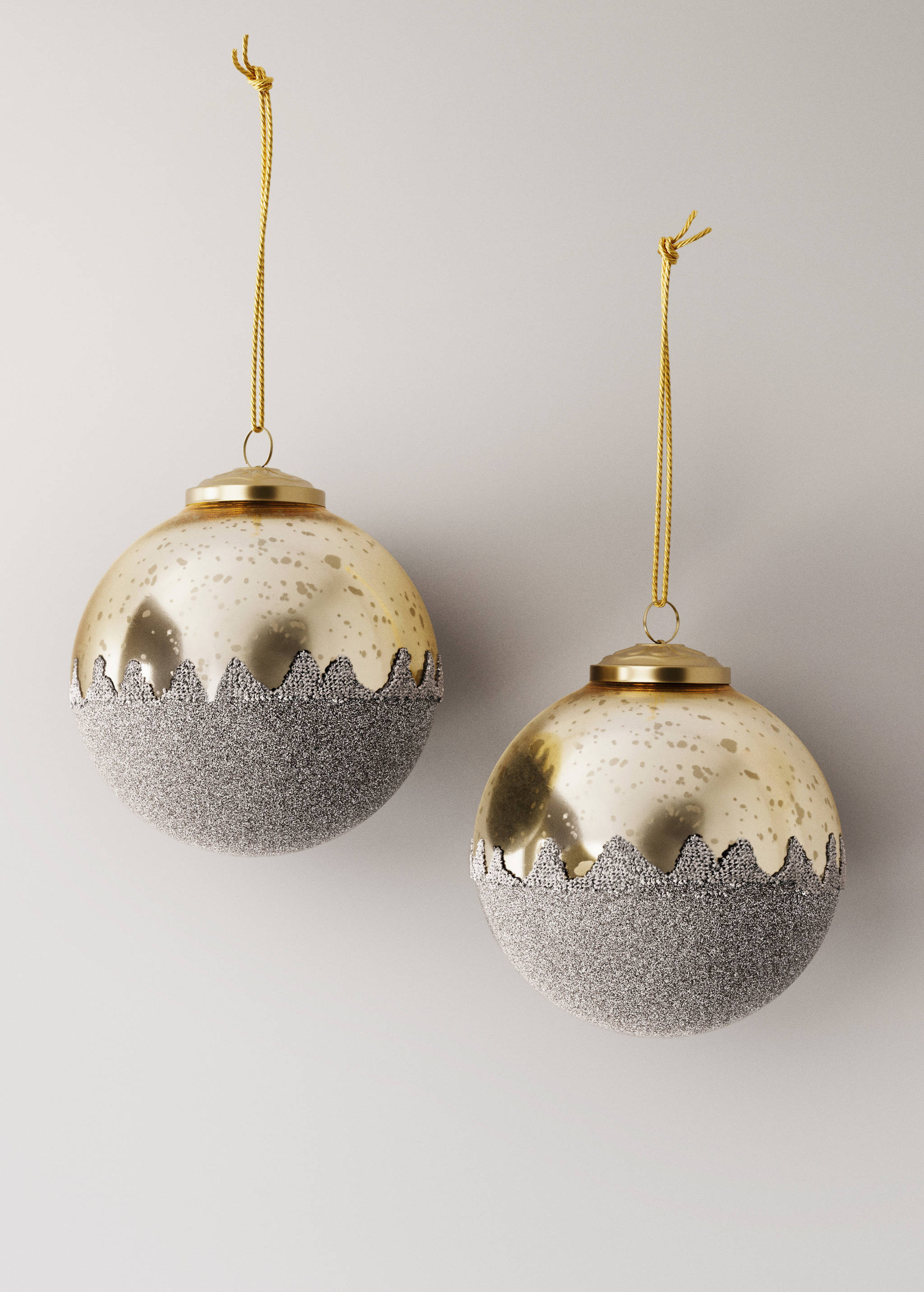 Two spherical Christmas ornaments with speckled gold tops and textured silver glitter lower halves.