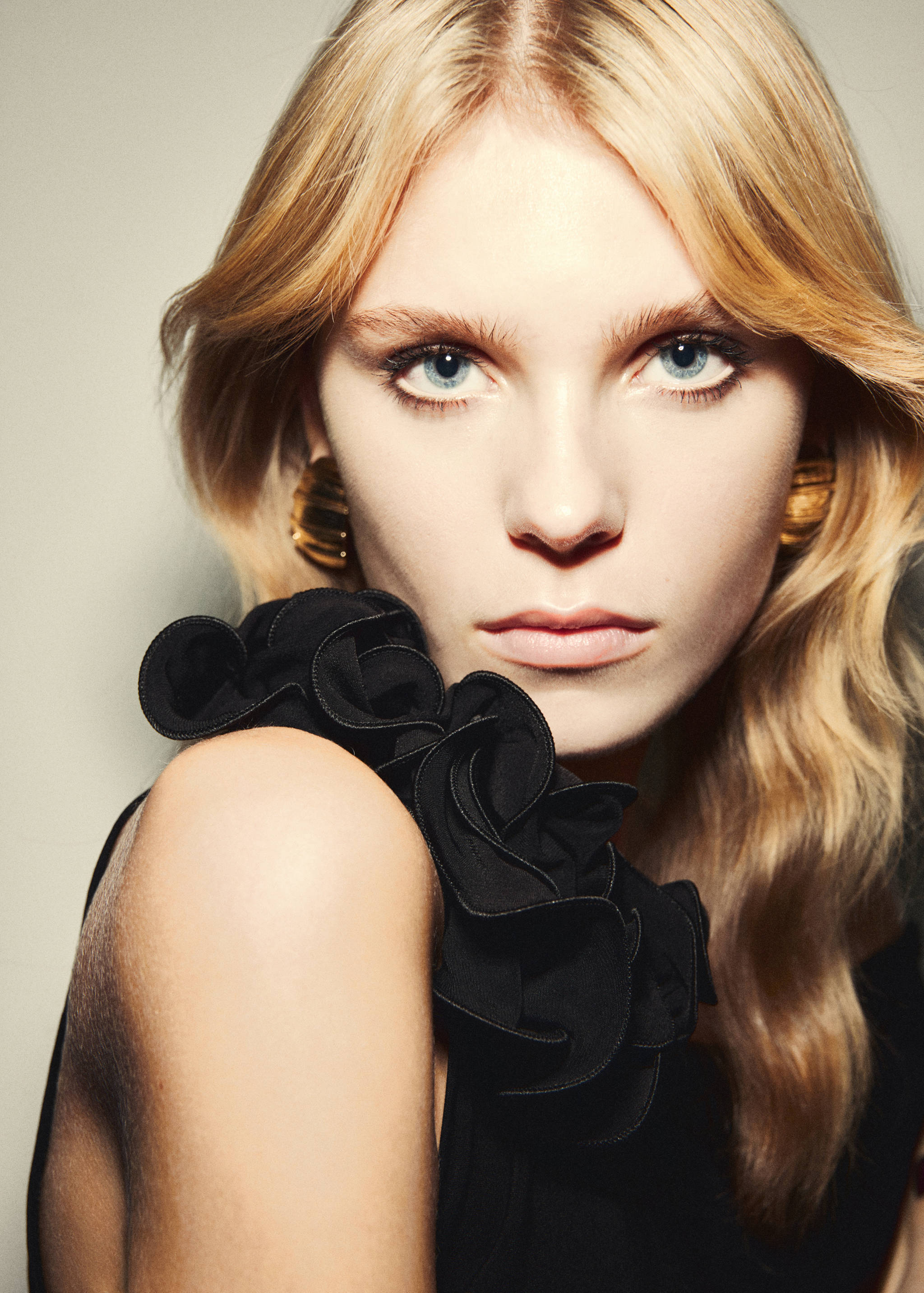 Close-up of a black dress with a ruffled floral shoulder strap.