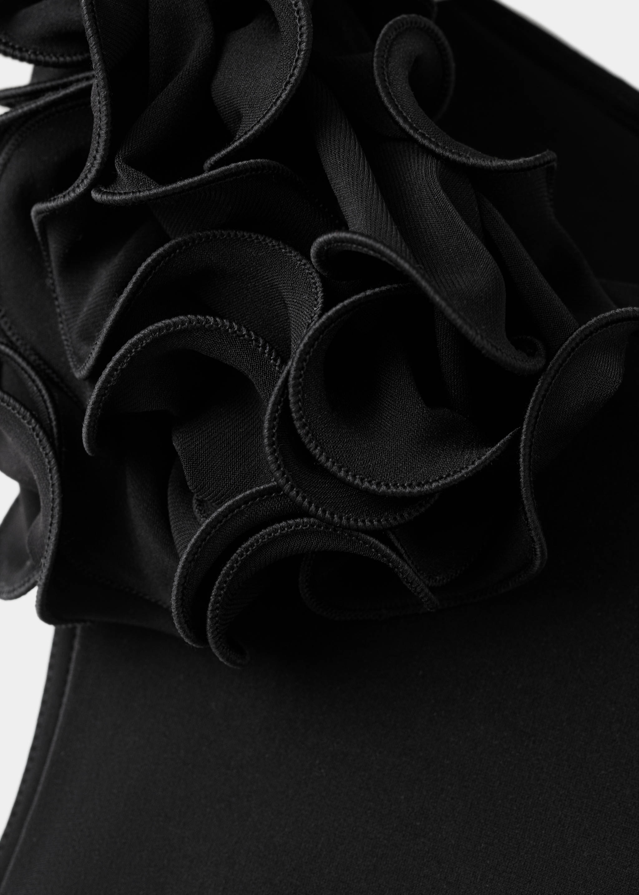 Black dress detail featuring a large sculptural fabric flower.