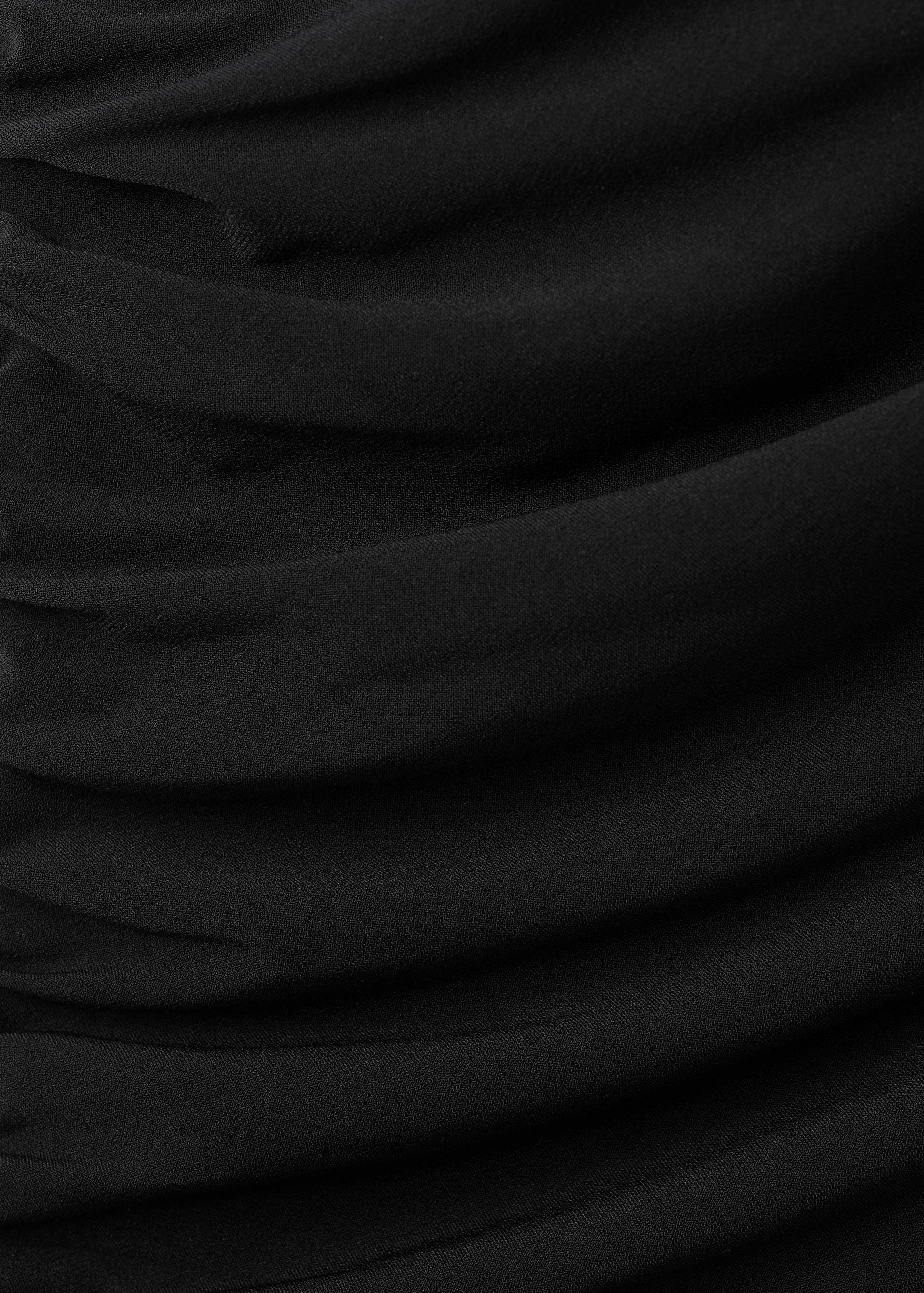 Close-up of black dress fabric featuring draped ruching.