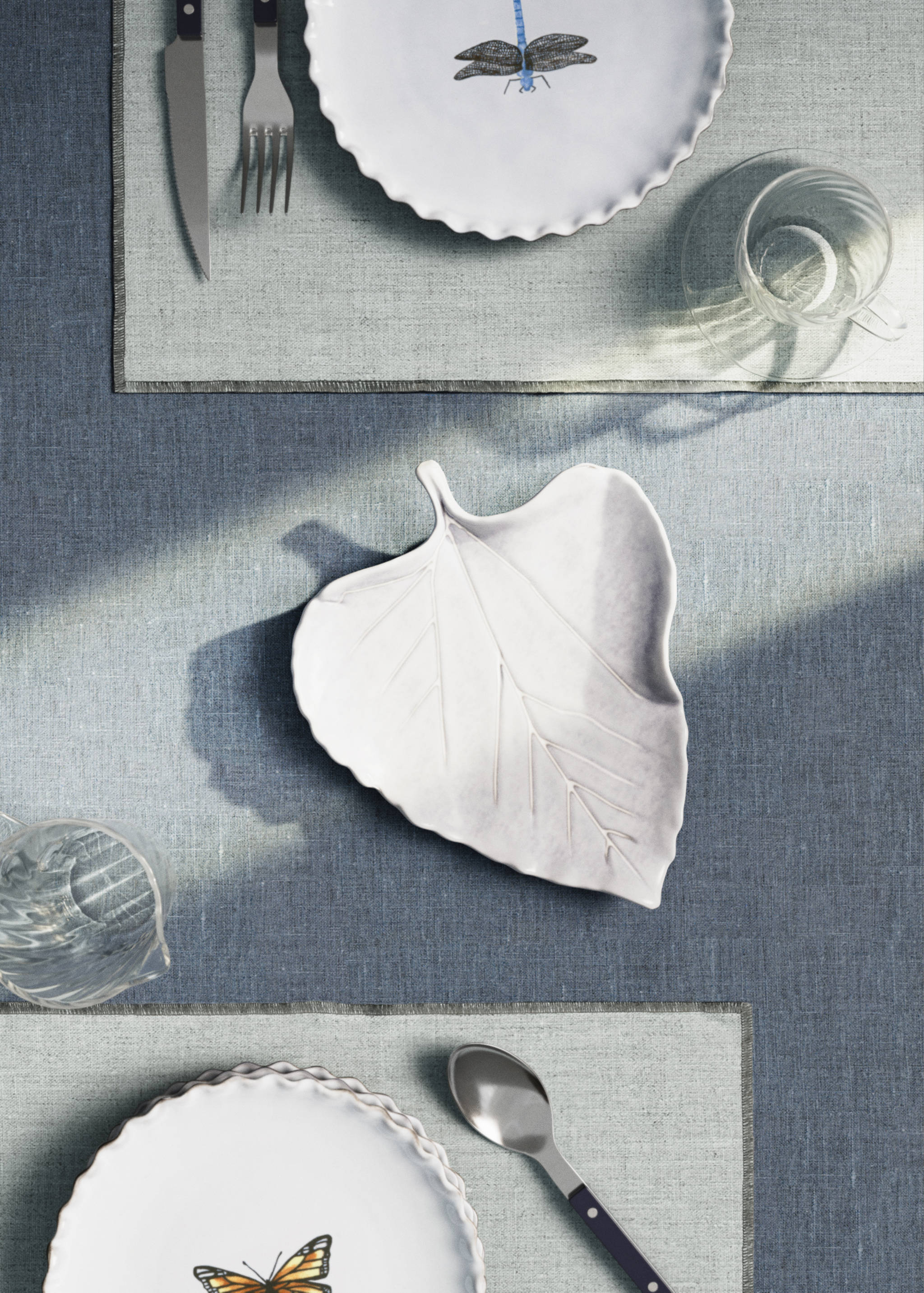 White leaf-shaped ceramic serving platter on a table setting.