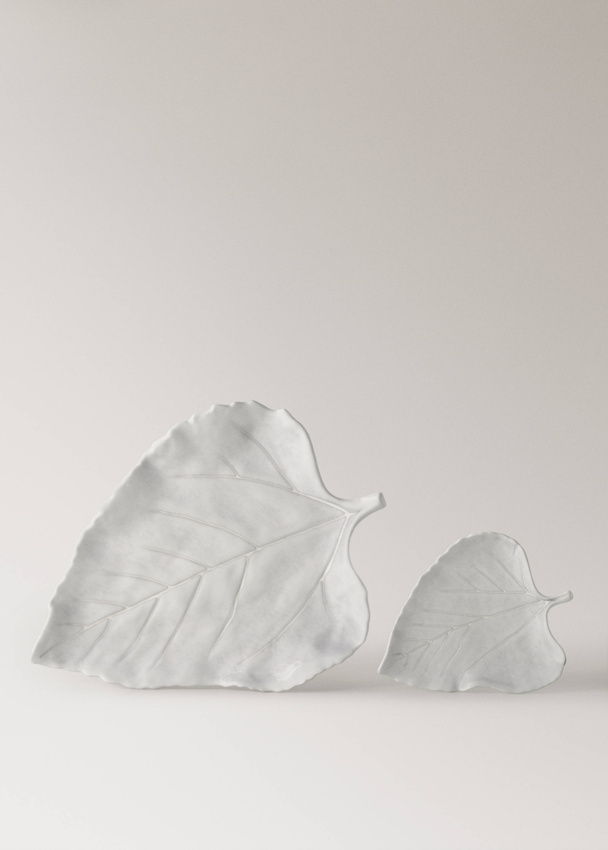 Two white leaf-shaped ceramic serving bowls with embossed vein detail.