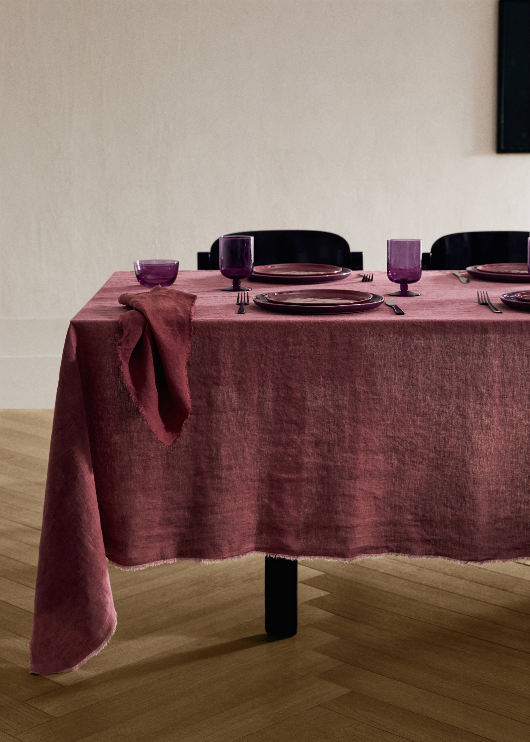 Dark pink fringed linen tablecloth on a set dining table.