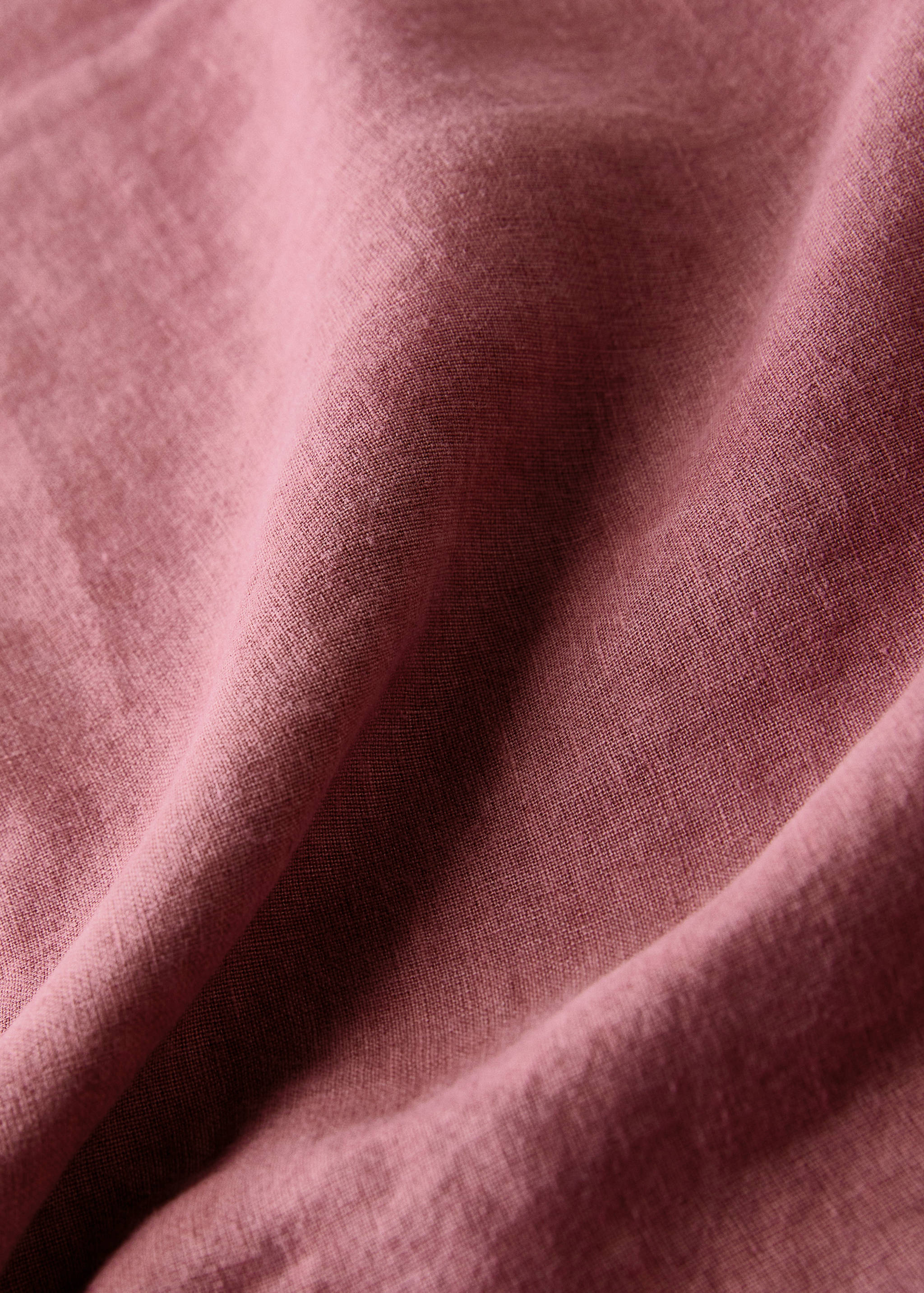 Dusty pink tablecloth fabric detail showing soft woven texture.