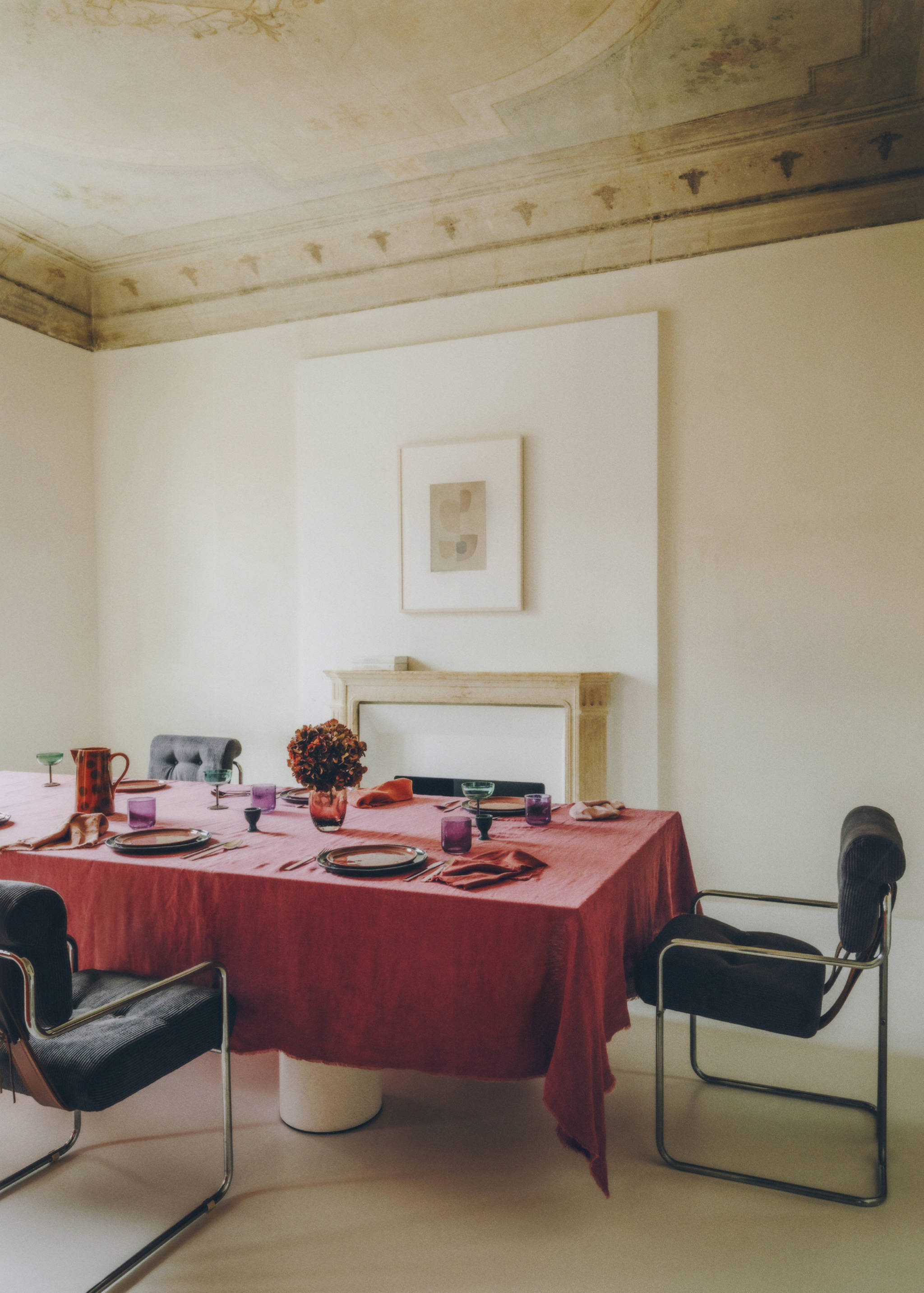 Red tablecloth with frayed edges set on a dining table in a minimalist room.