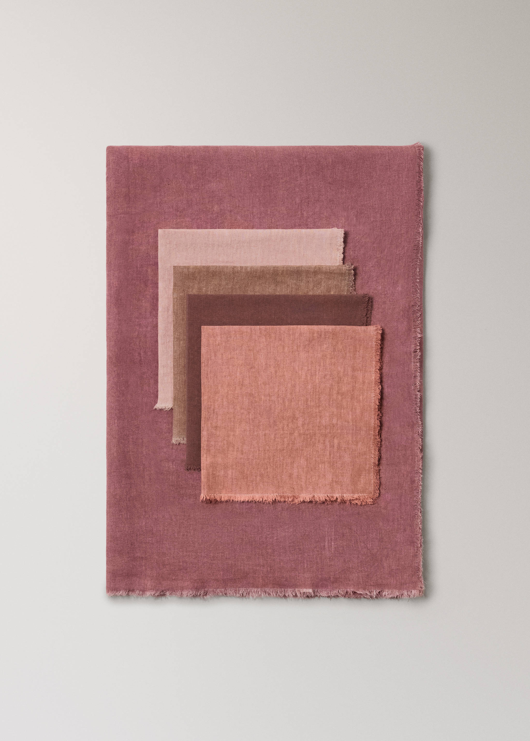 Dark mauve tablecloth with fringed edges styled with layered square napkins.