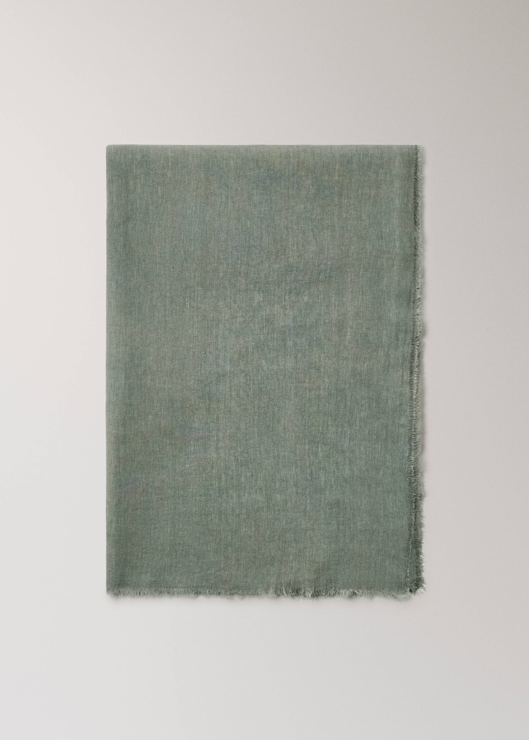 Green tablecloth with textured woven fabric and frayed fringe detail.