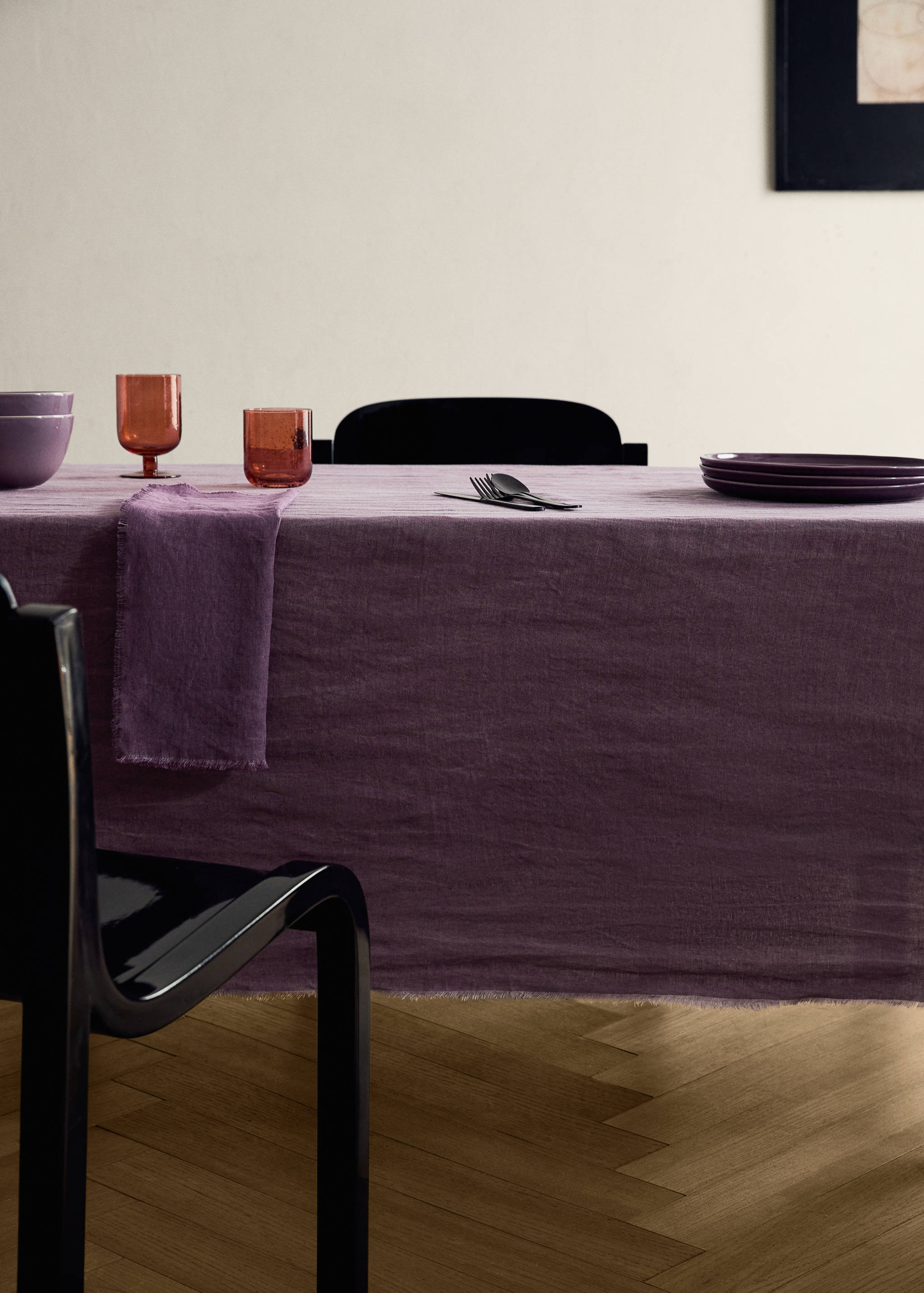 Purple tablecloth with fringed edges on a set dining table.