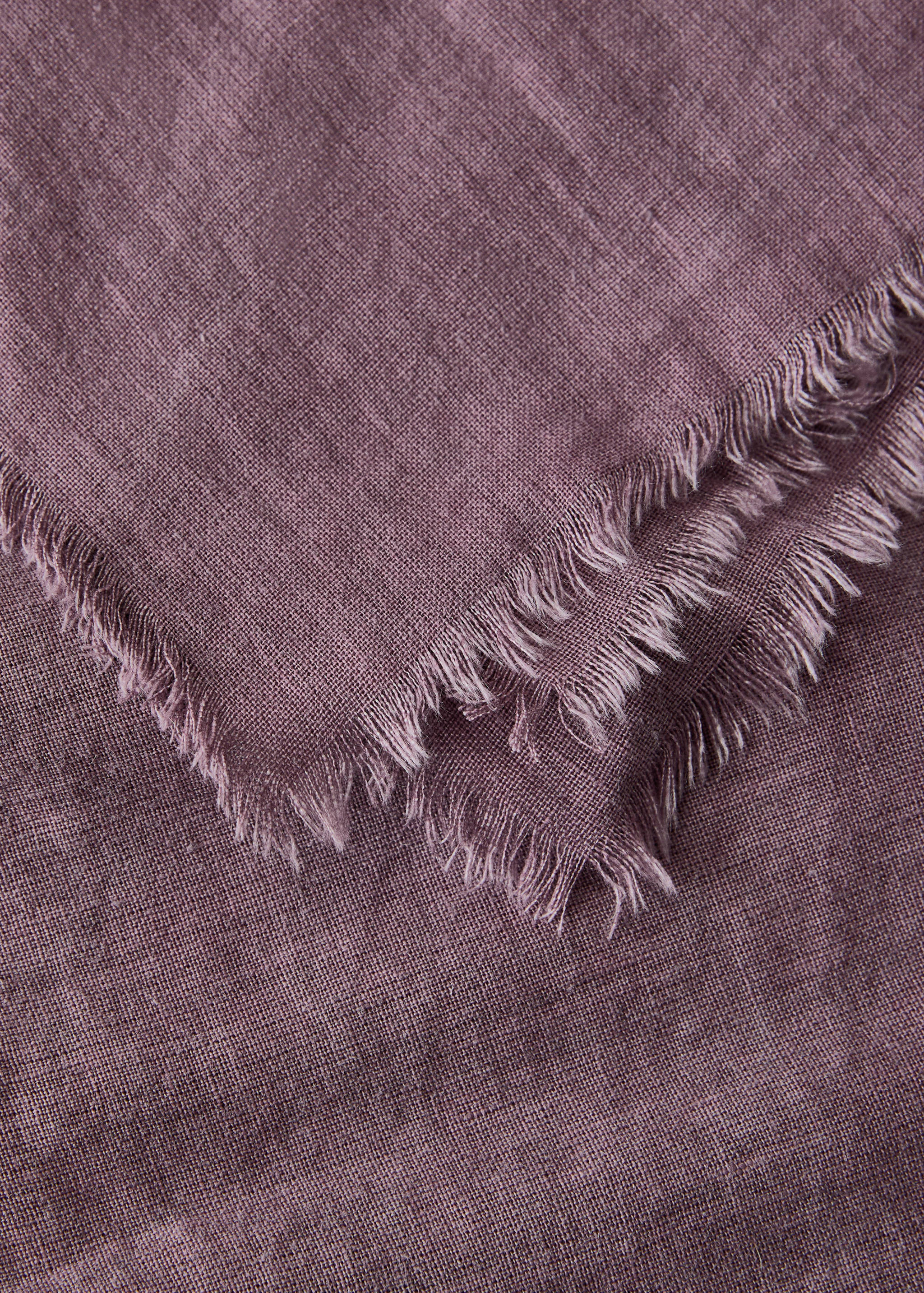 Close-up of a mauve tablecloth with fringed edges and textured fabric.