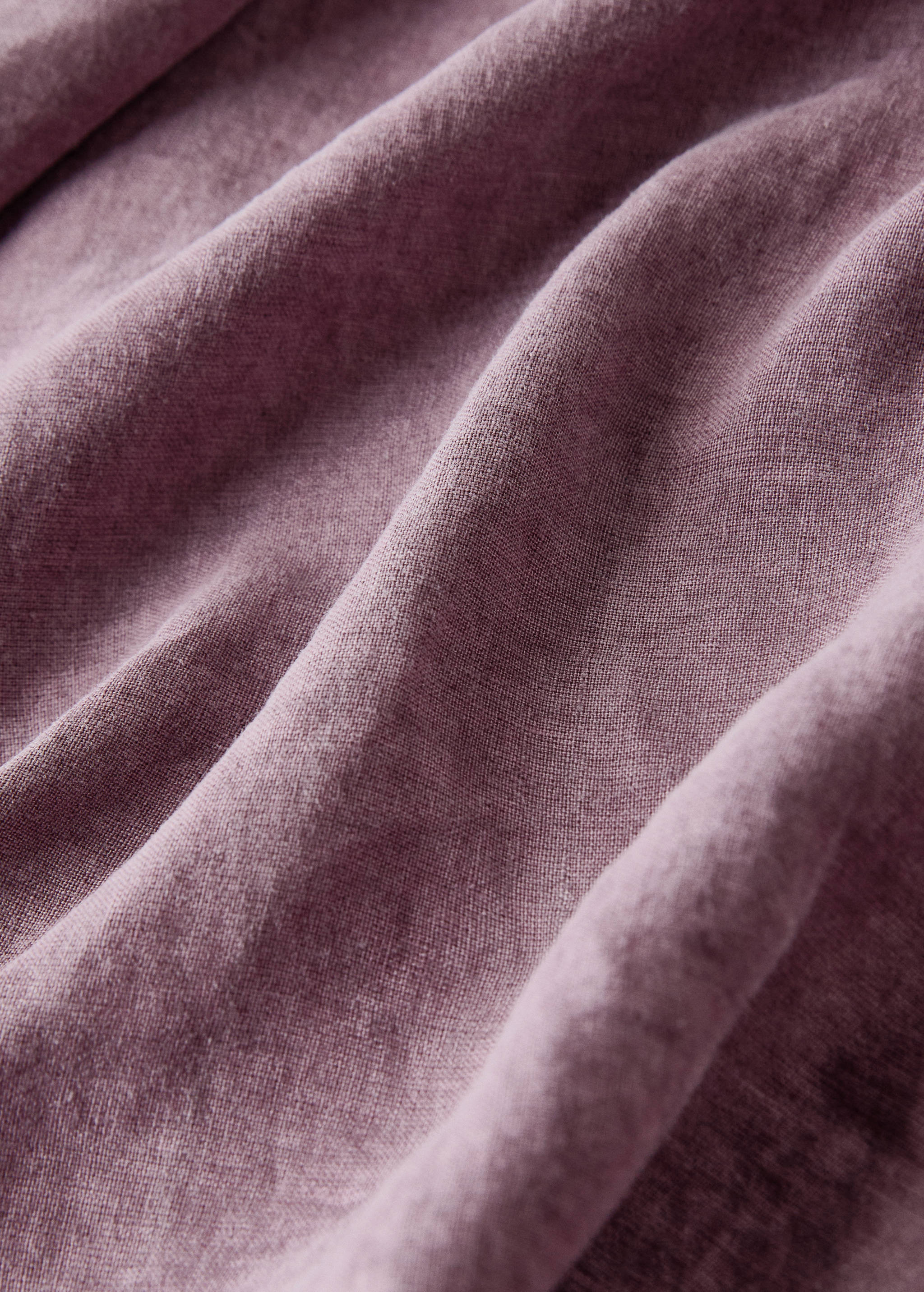 Close-up of a textured mauve-pink tablecloth fabric.