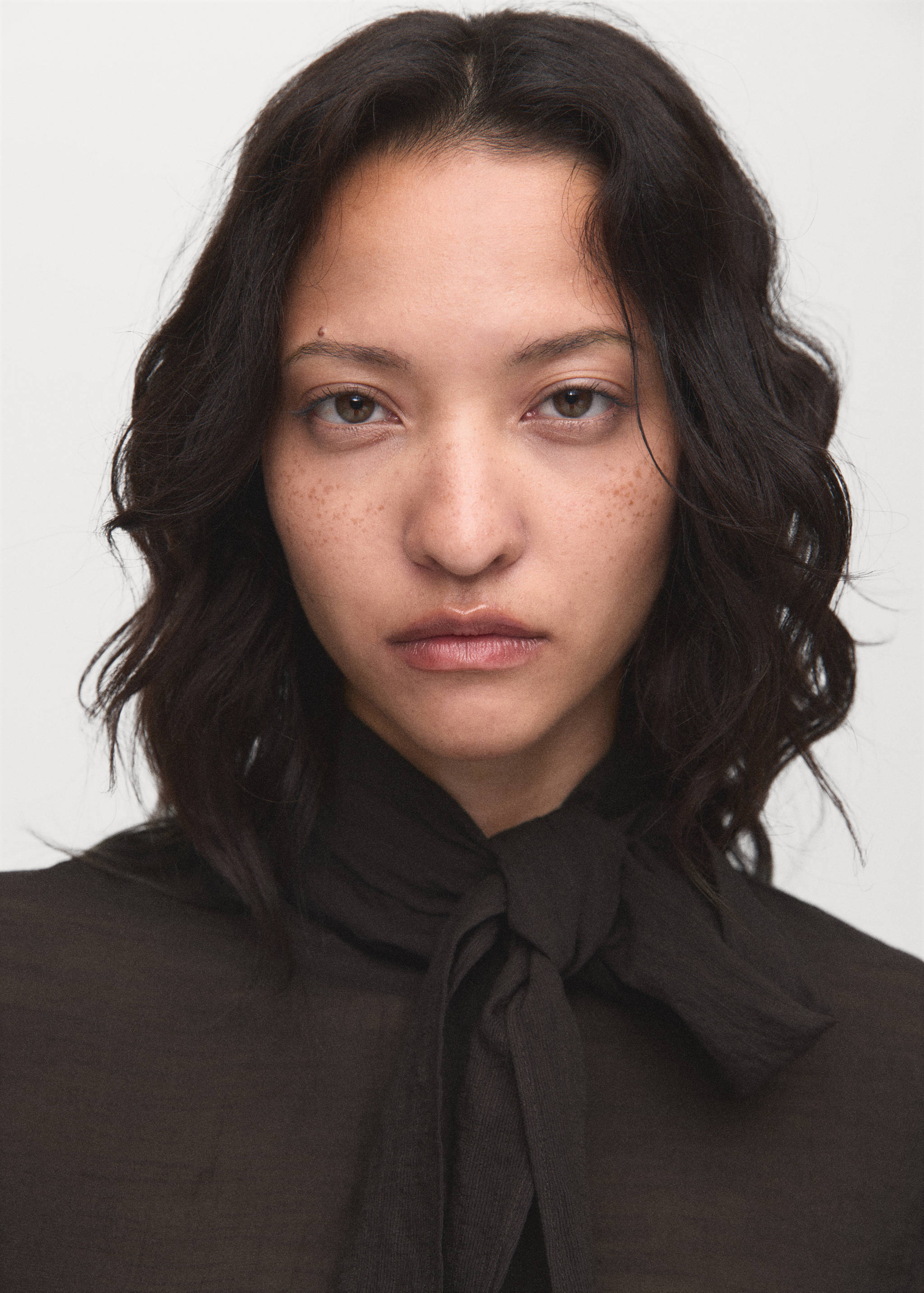 Close-up of a dark brown blouse with a high tied neckline.