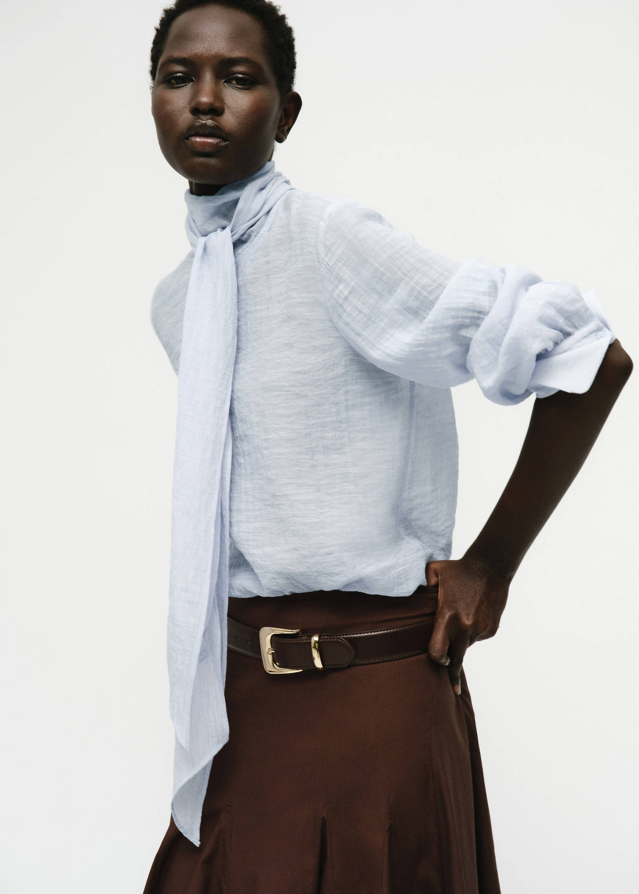 Light blue textured blouse with high neck and attached scarf tie.