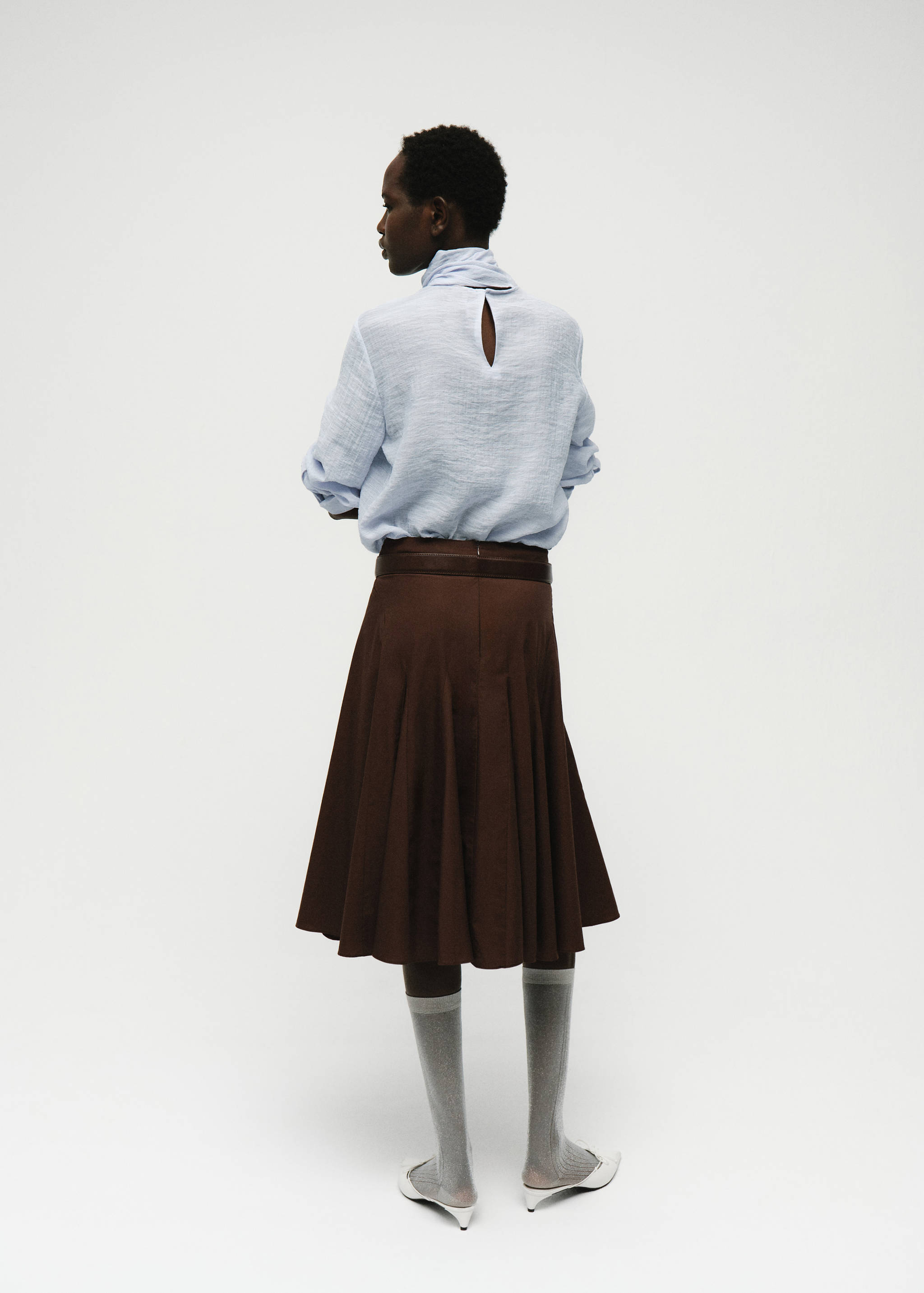 Light blue textured blouse from the back, featuring a high neck and teardrop cutout.