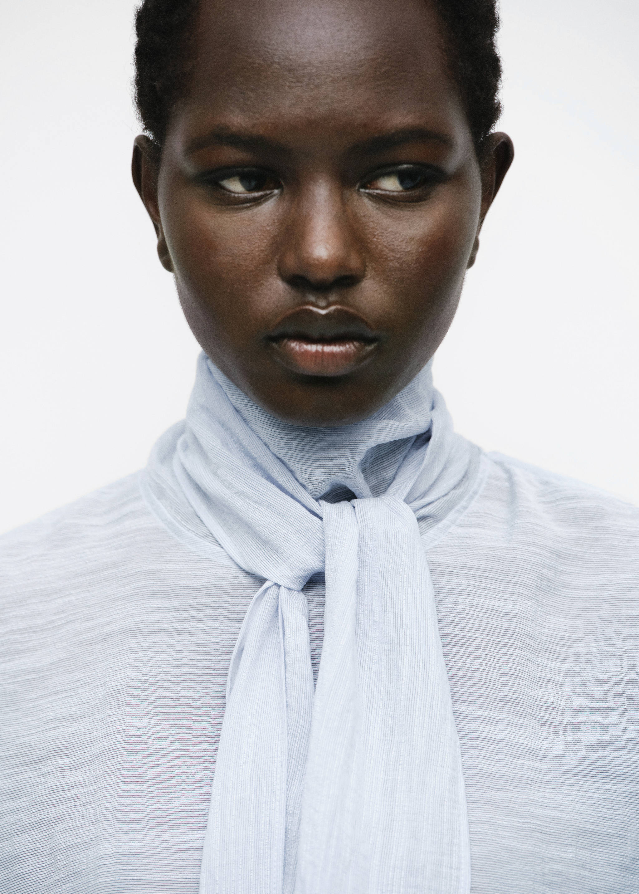 Light blue textured blouse with a high neck and front scarf tie.