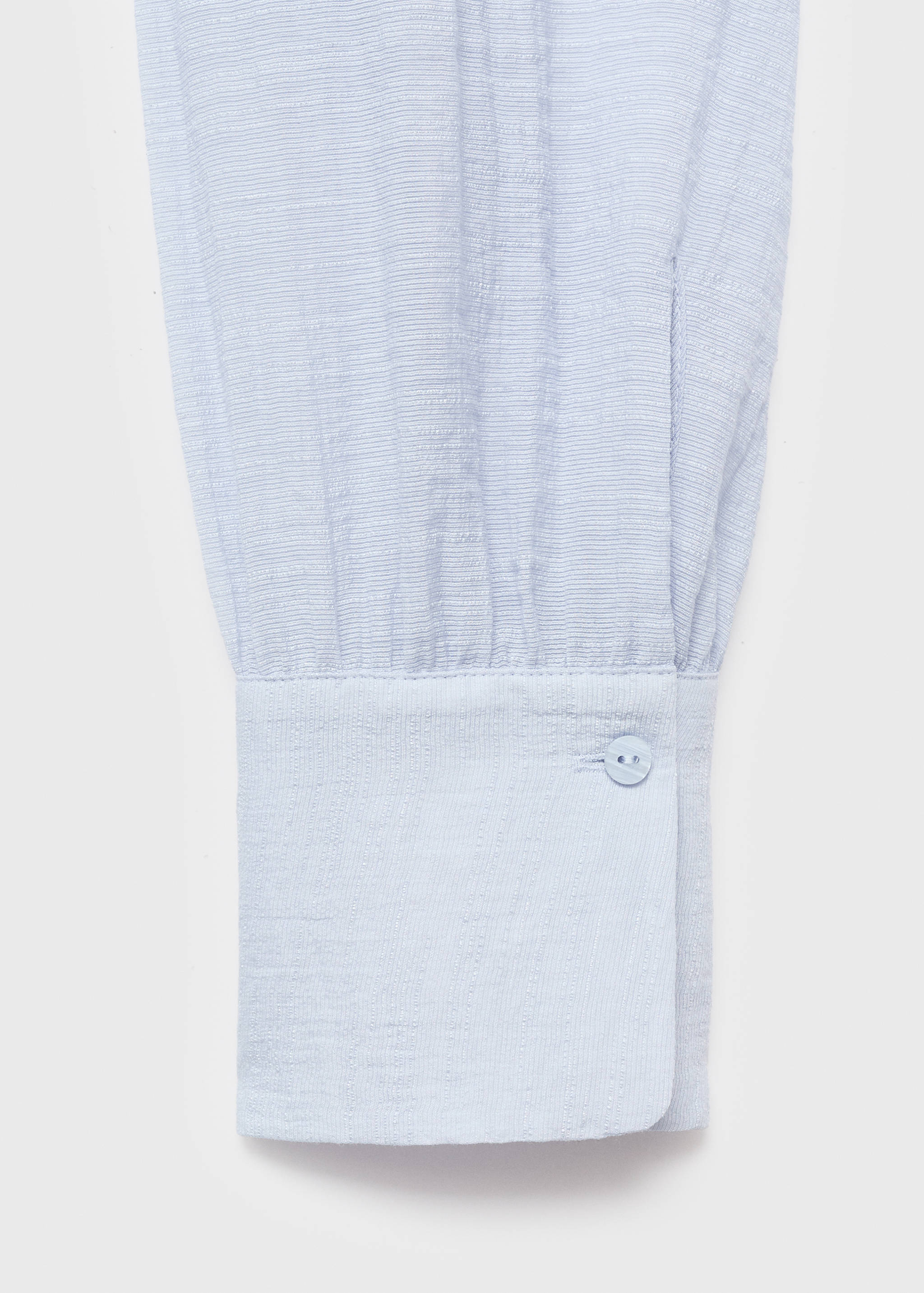 Close-up of a light blue blouse sleeve with a buttoned cuff.