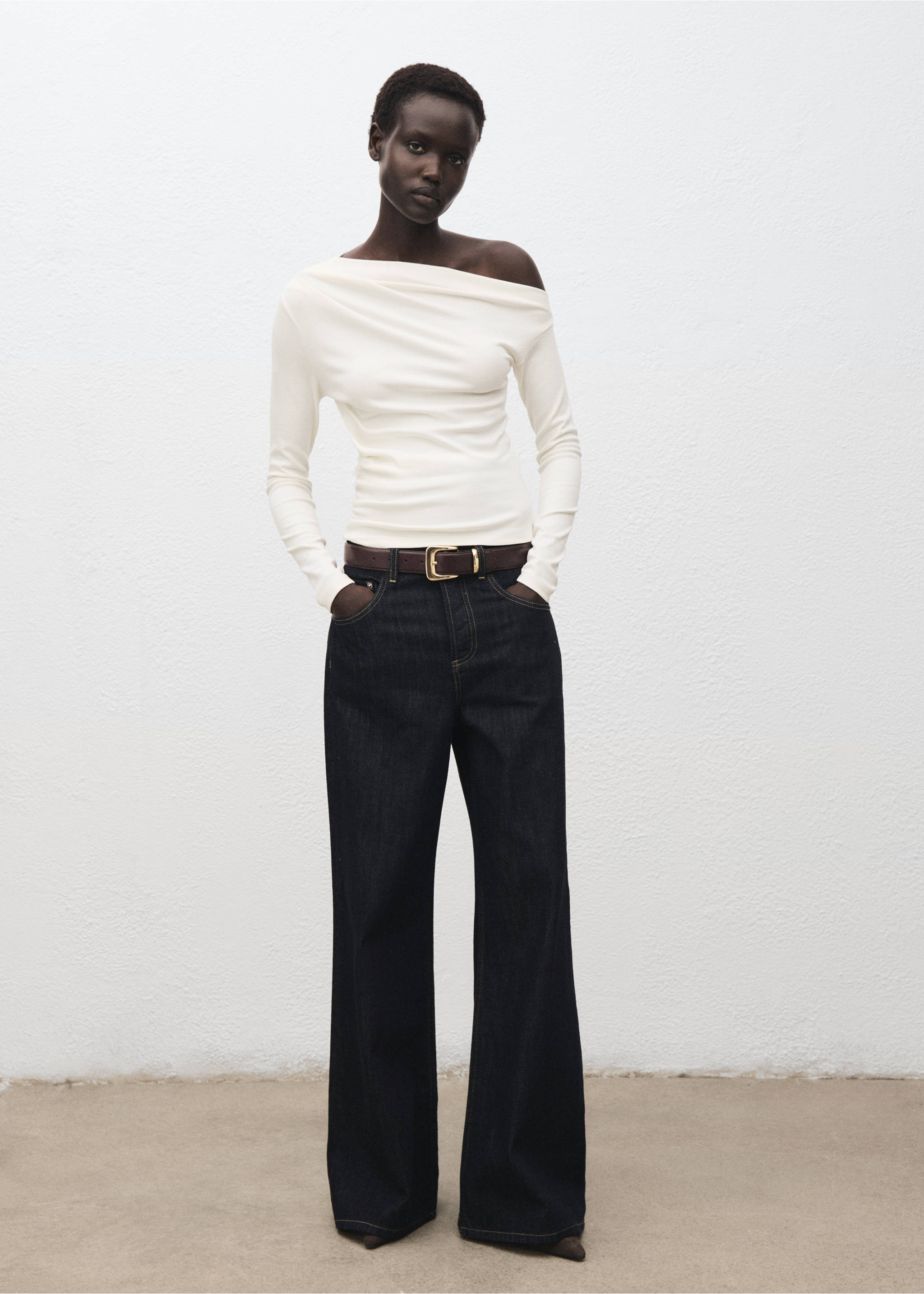White off-the-shoulder long-sleeve t-shirt with draped neckline worn with dark blue trousers., Off White. Ref: 17045827-00.