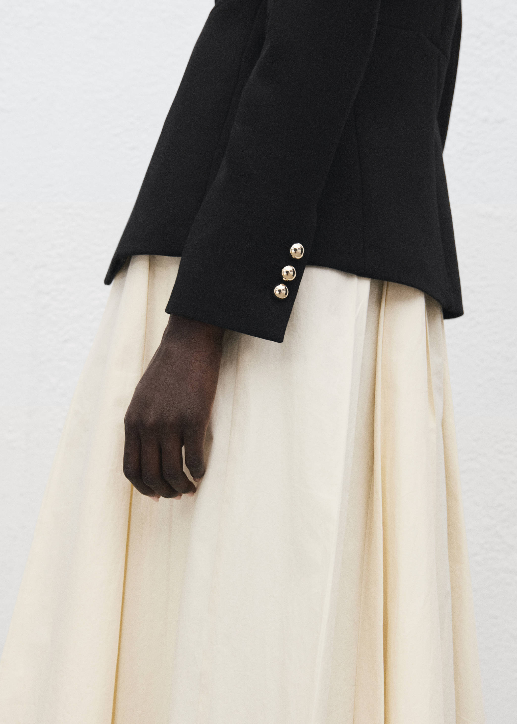 Close-up of a black jacket sleeve cuff with gold metallic buttons.