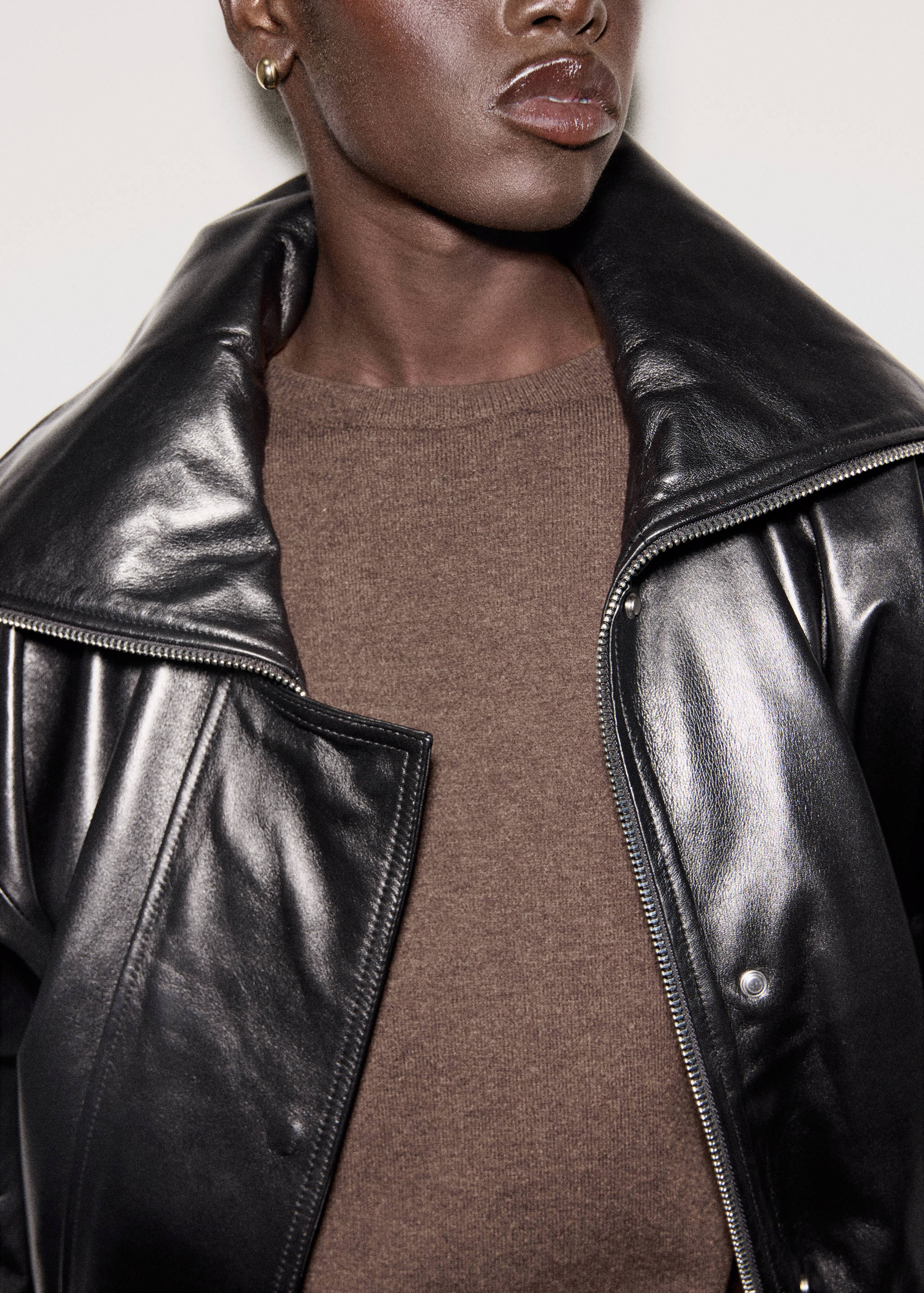 Vestido marrón de punto combinado con chaqueta negra de piel de cuello alto.